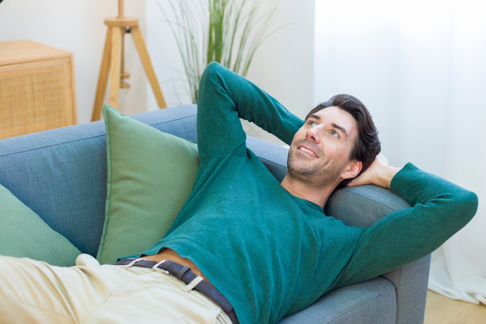 White man relaxing on couch in cozy living room at home