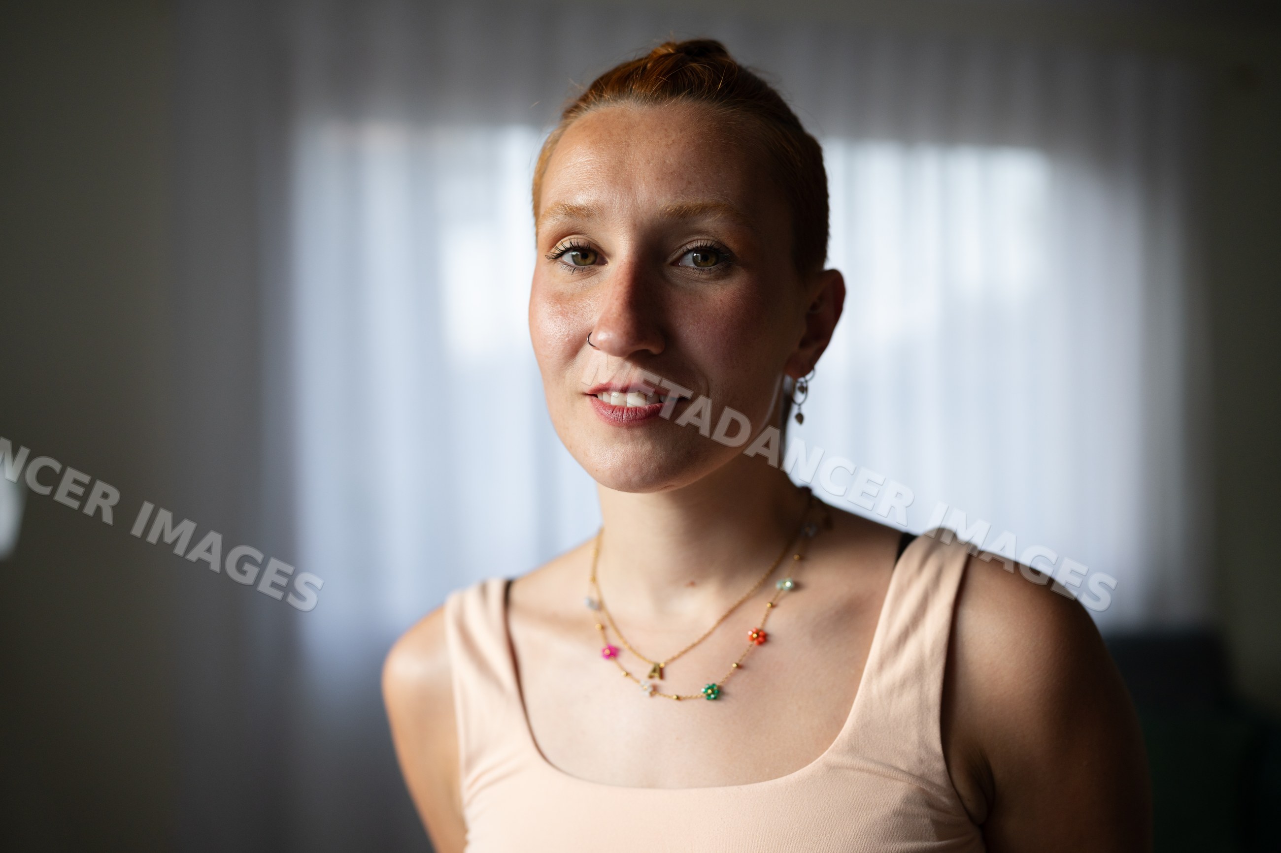 A white woman smiles softly at home in Galicia, spain wearing jewelry