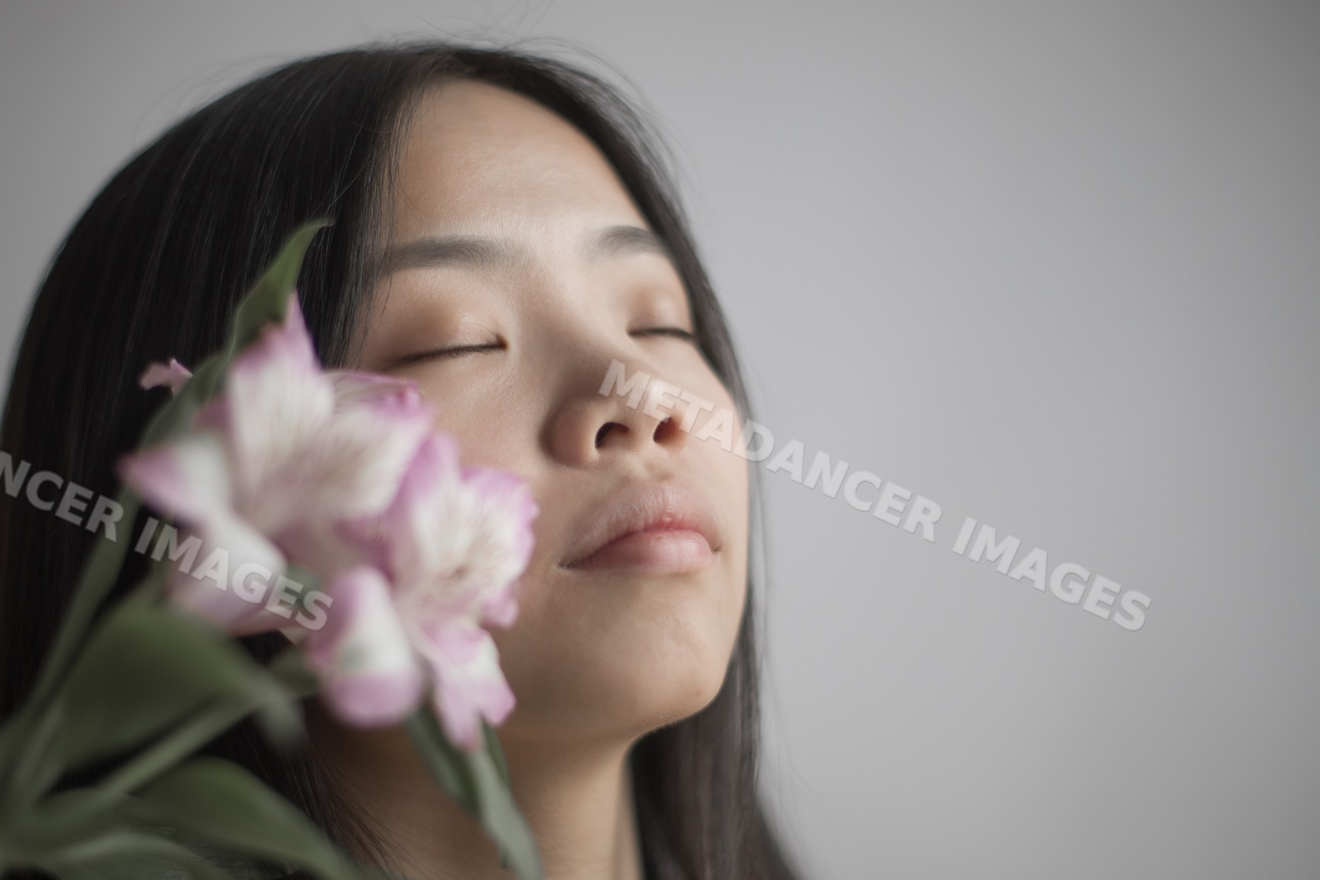 Portrait of a Southeast Asian woman holding pink flower with closed