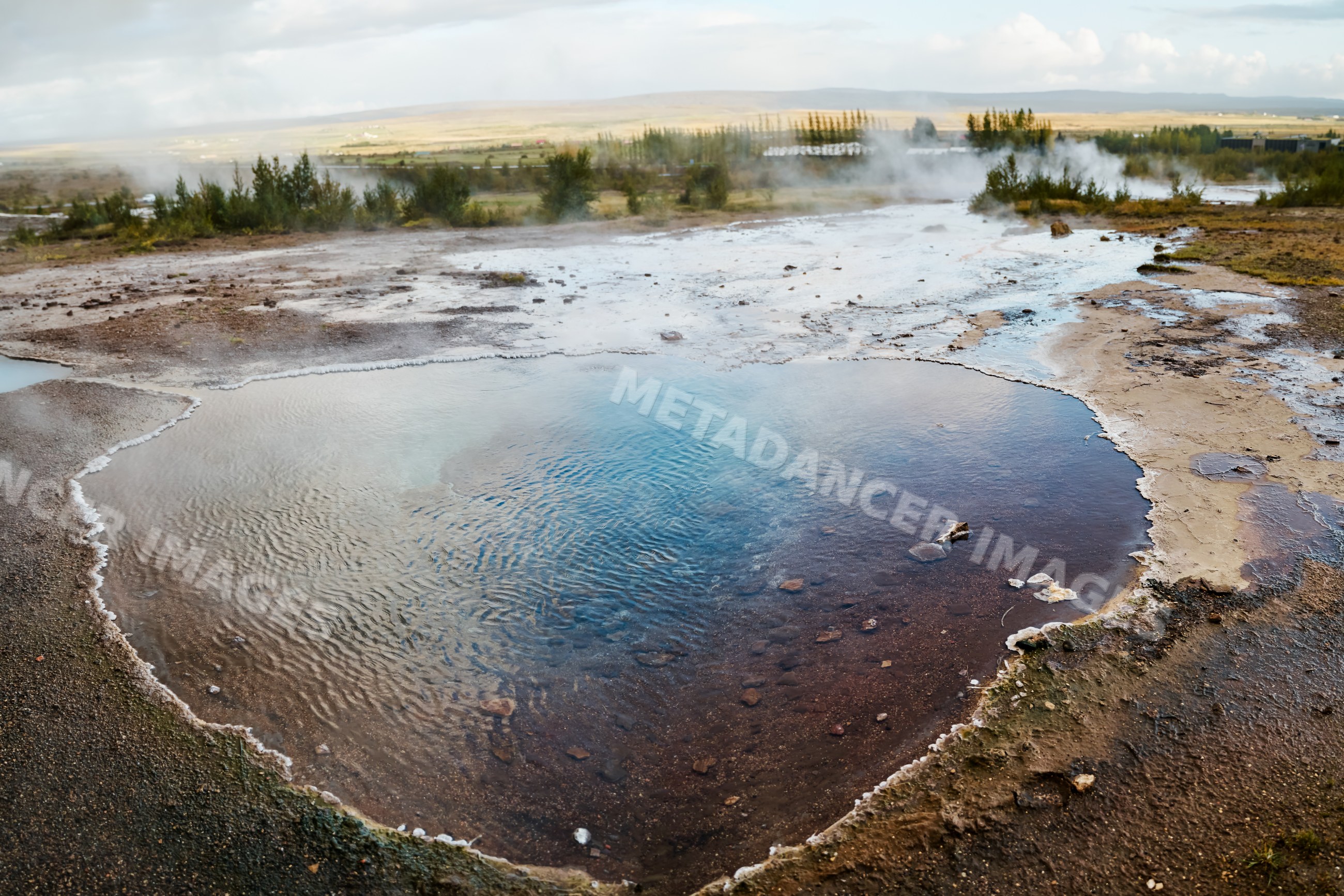 Geothermal hot spring with rising steam in Iceland's natural landscape