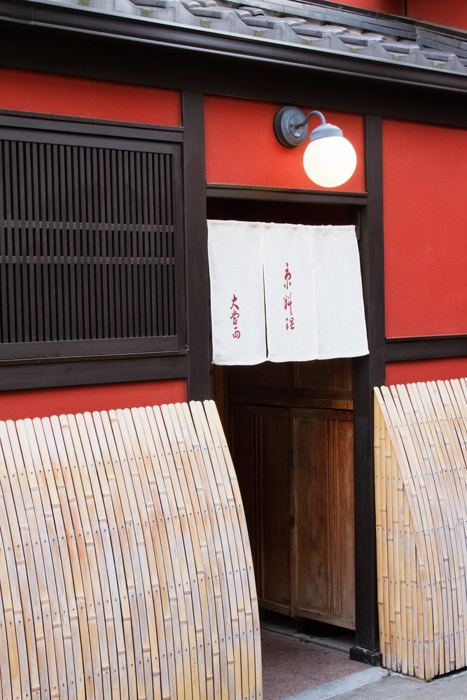 Entrance of a red-painted wooden building with a white paper noren