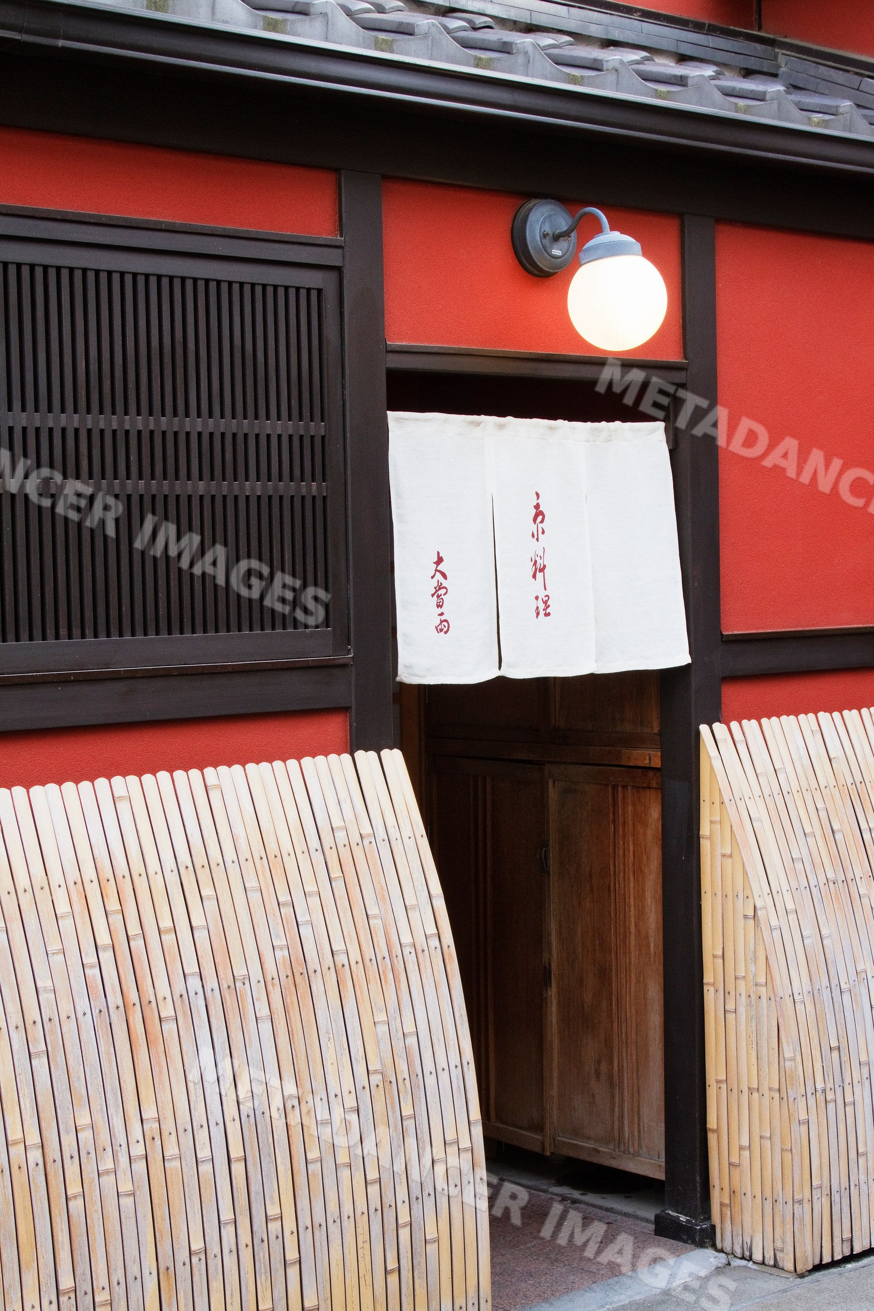 Entrance of a red-painted wooden building with a white paper noren