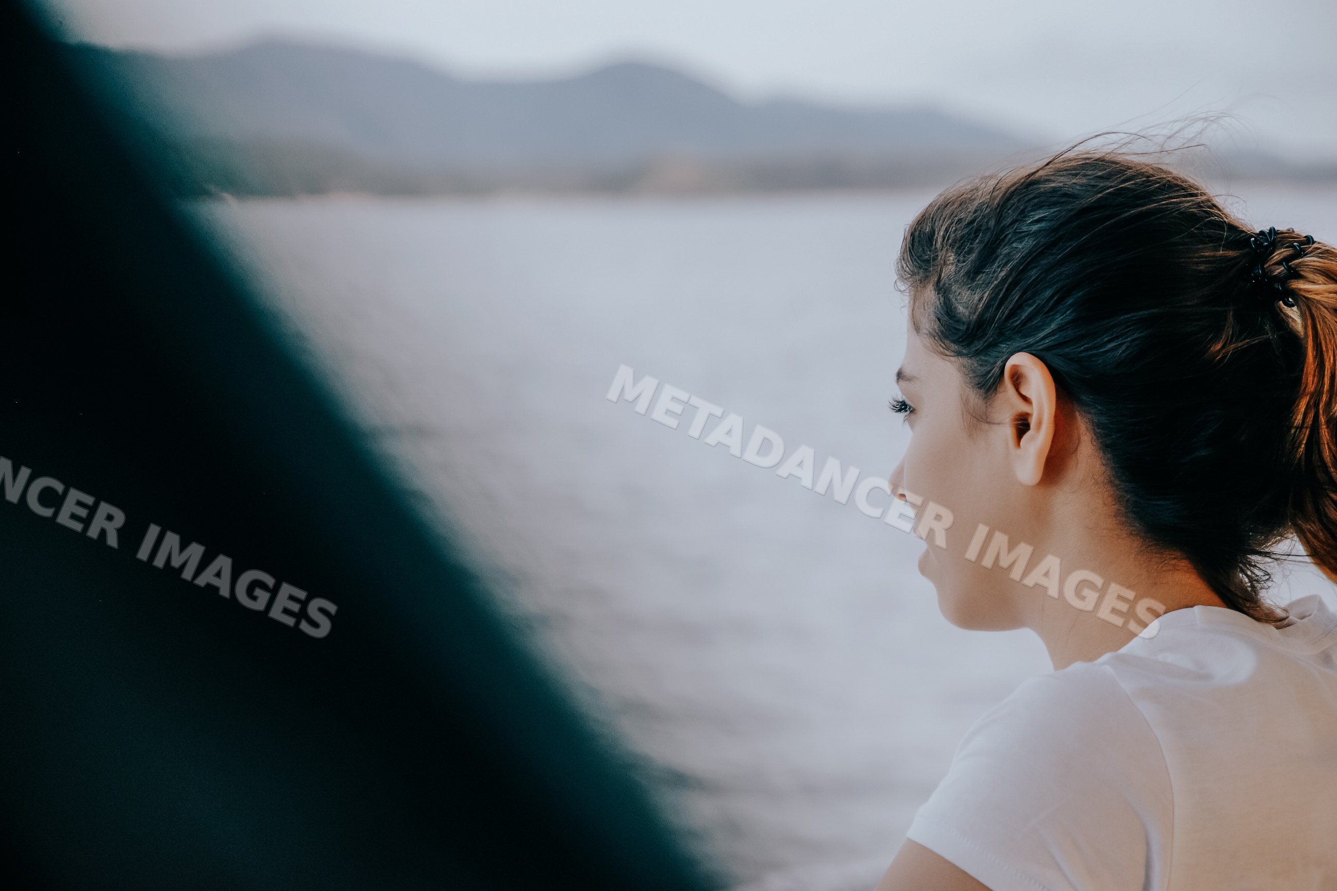 White woman gazing at the sea from boat with mountain landscape