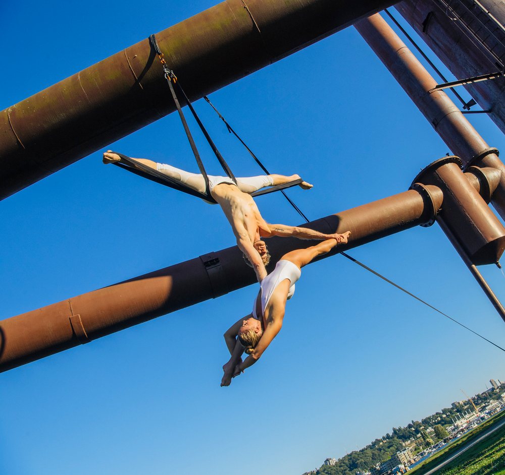 Two acrobats performing aerial straps act outdoors in Seattle