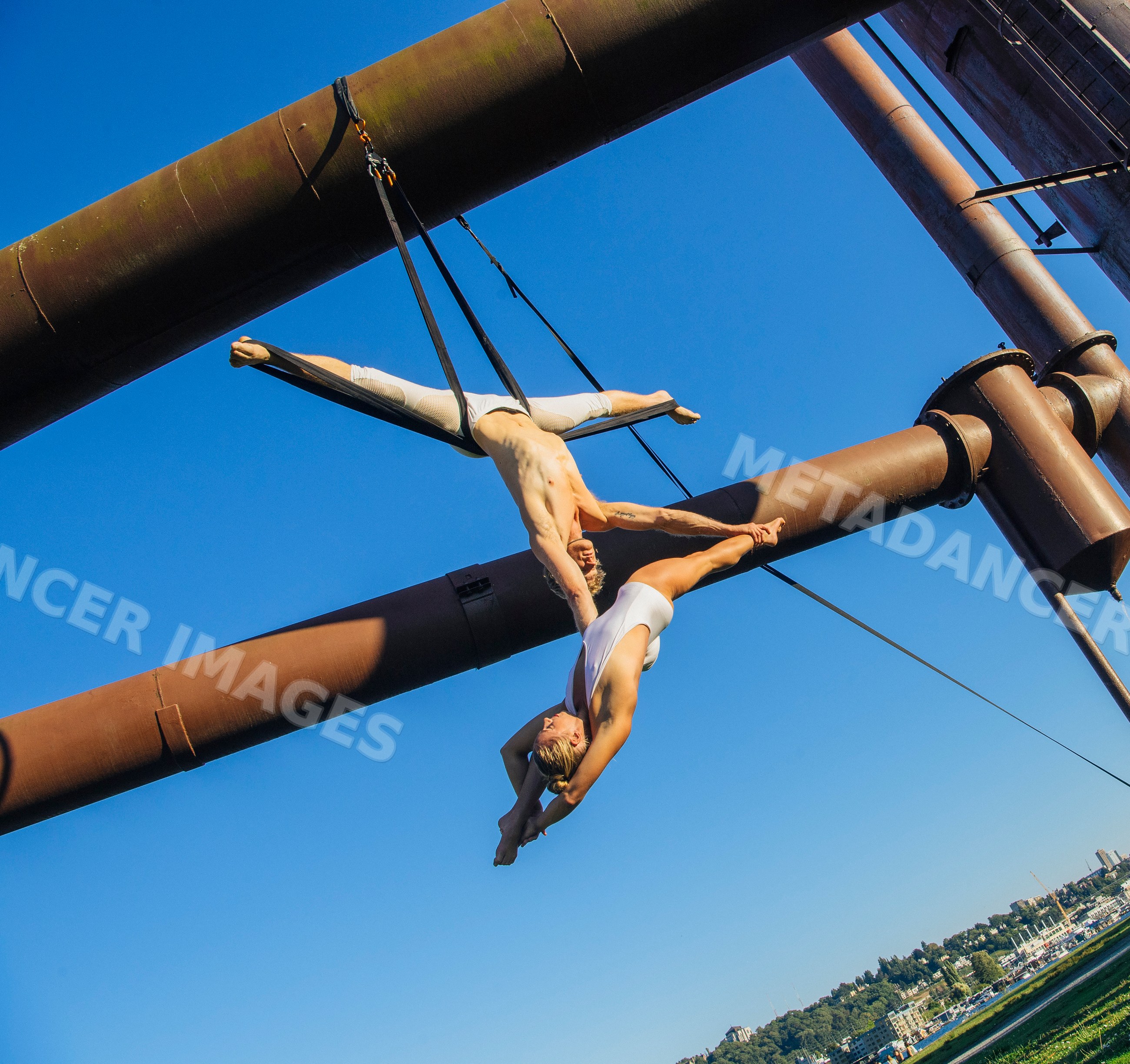 Two acrobats performing aerial straps act outdoors in Seattle