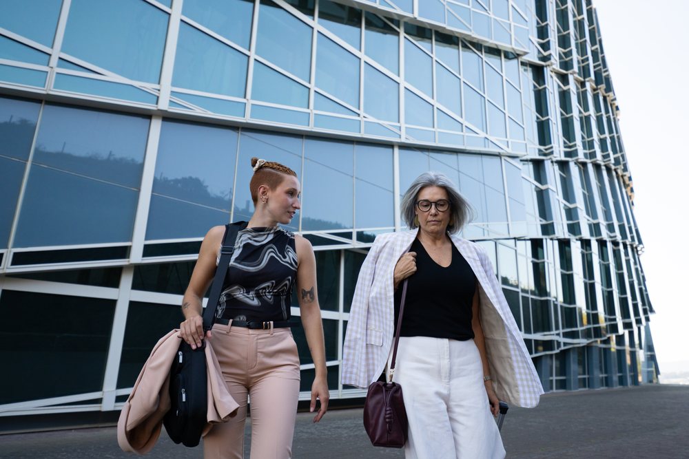 Two businesswomen walking by modern glass building