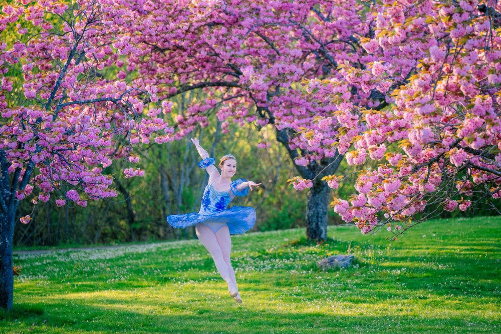 A ballet dancer gracefully leaps outdoors