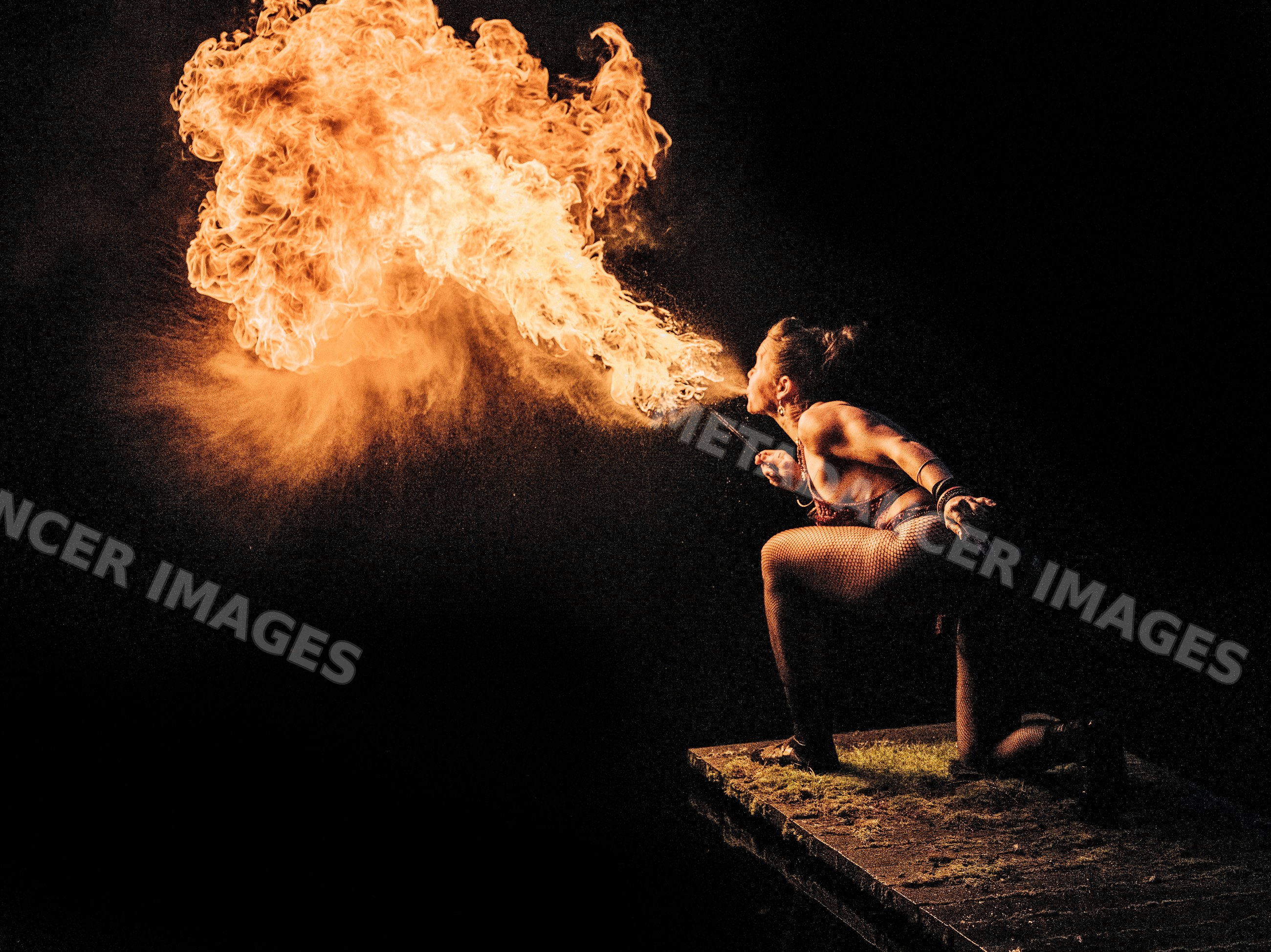 Fire breather performing with flame in dark setting