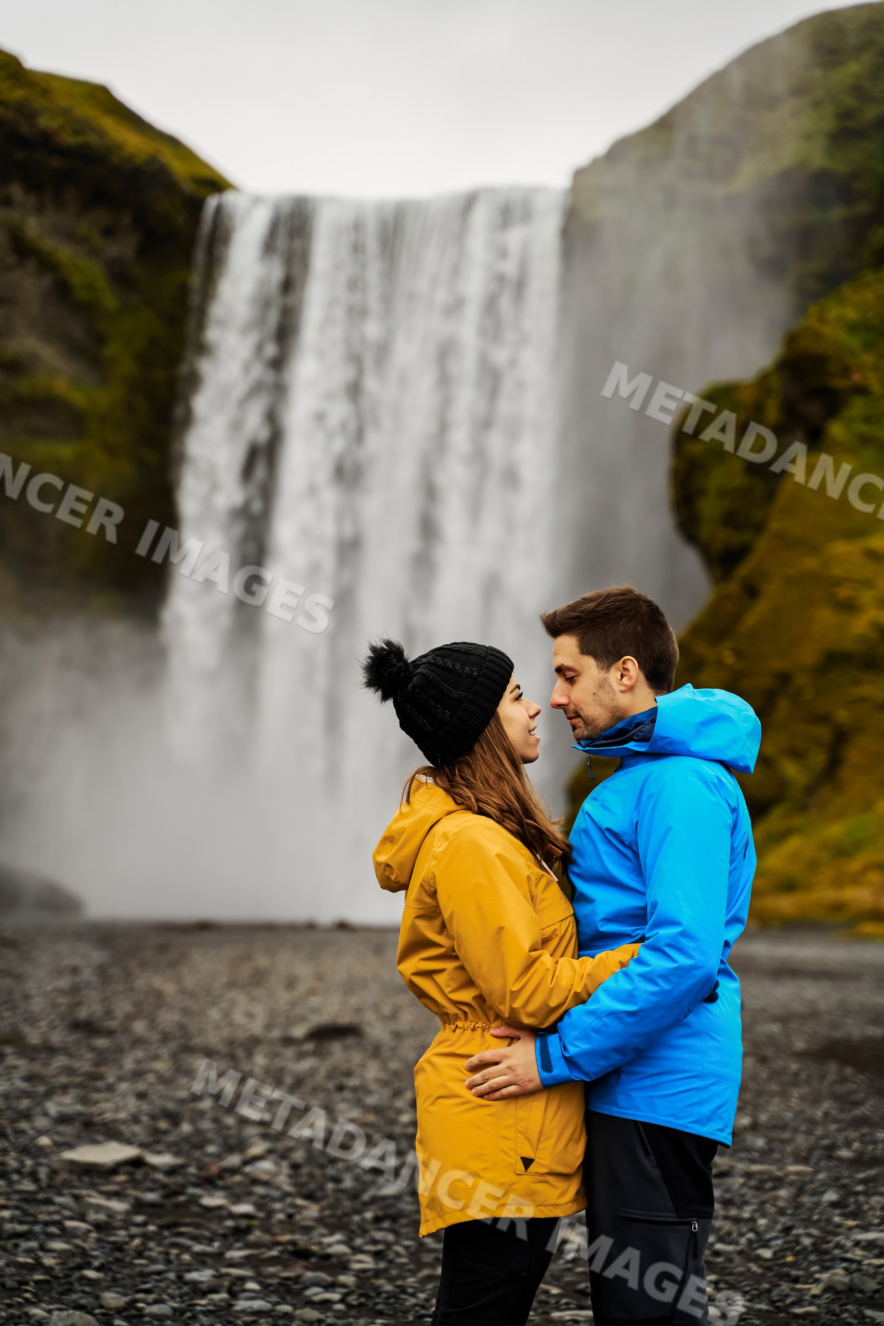 A couple embraces near a waterfall in Iceland