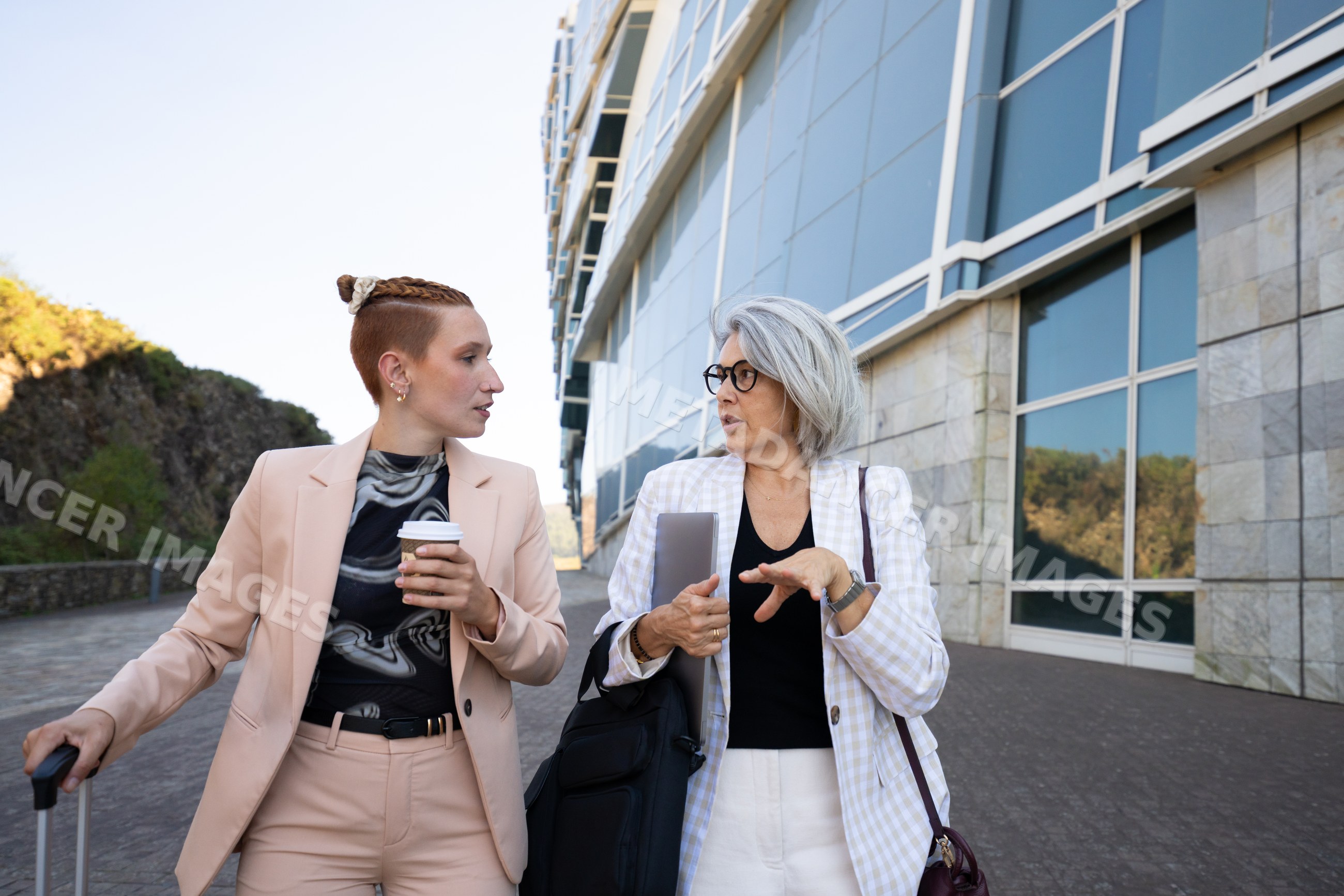 Businesswomen walking and talking outside modern office building