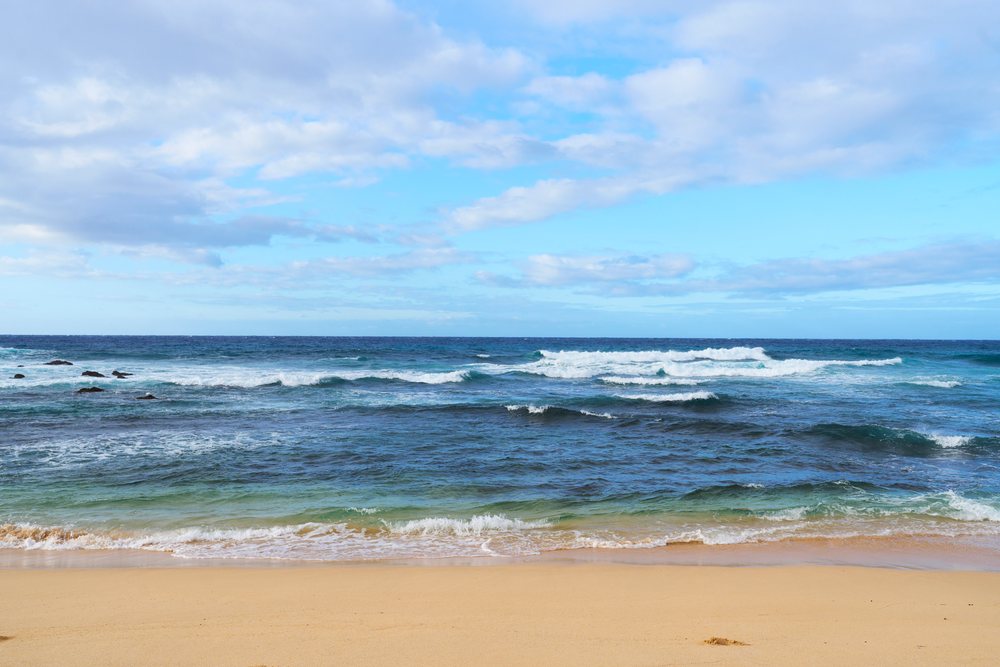 Ocean waves rolling onto sandy beach under blue sky in a beach