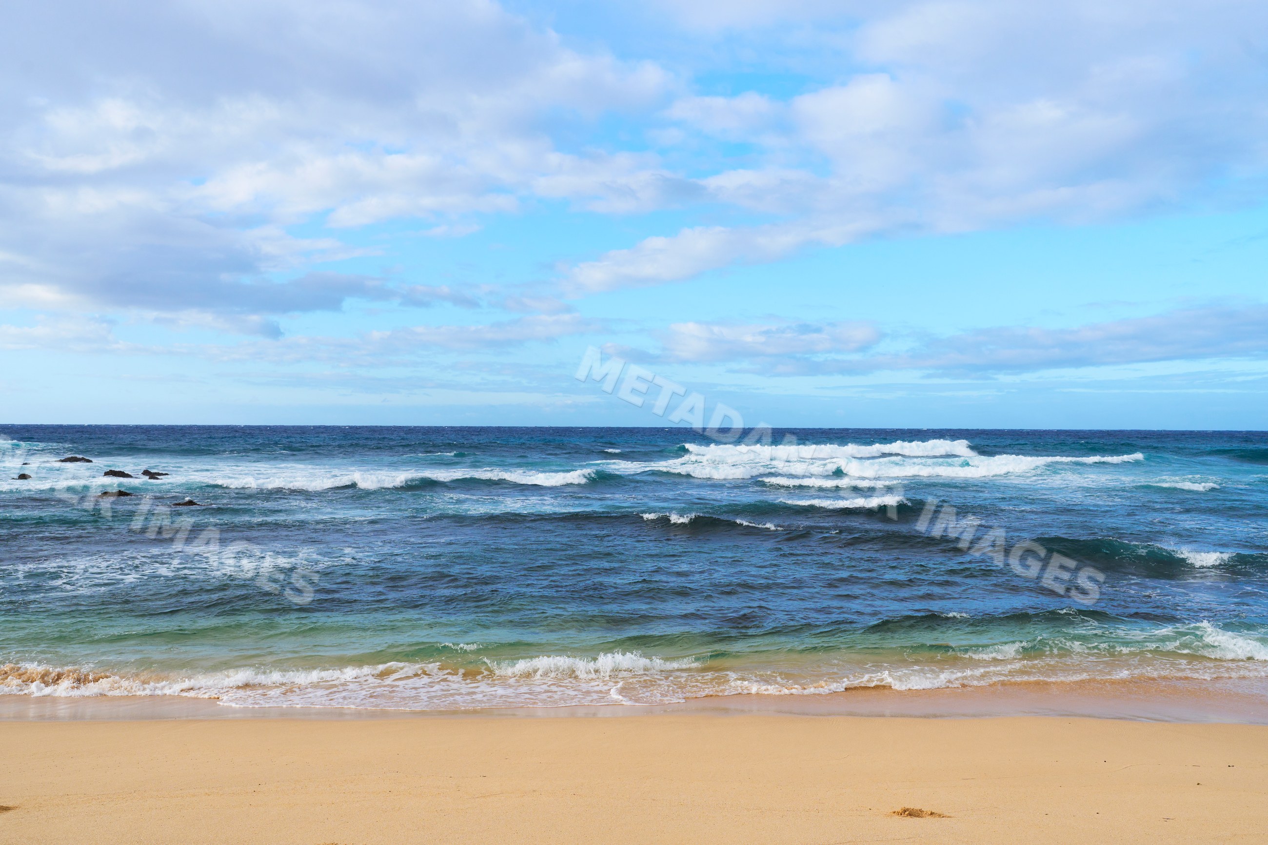 Ocean waves rolling onto sandy beach under blue sky in a beach