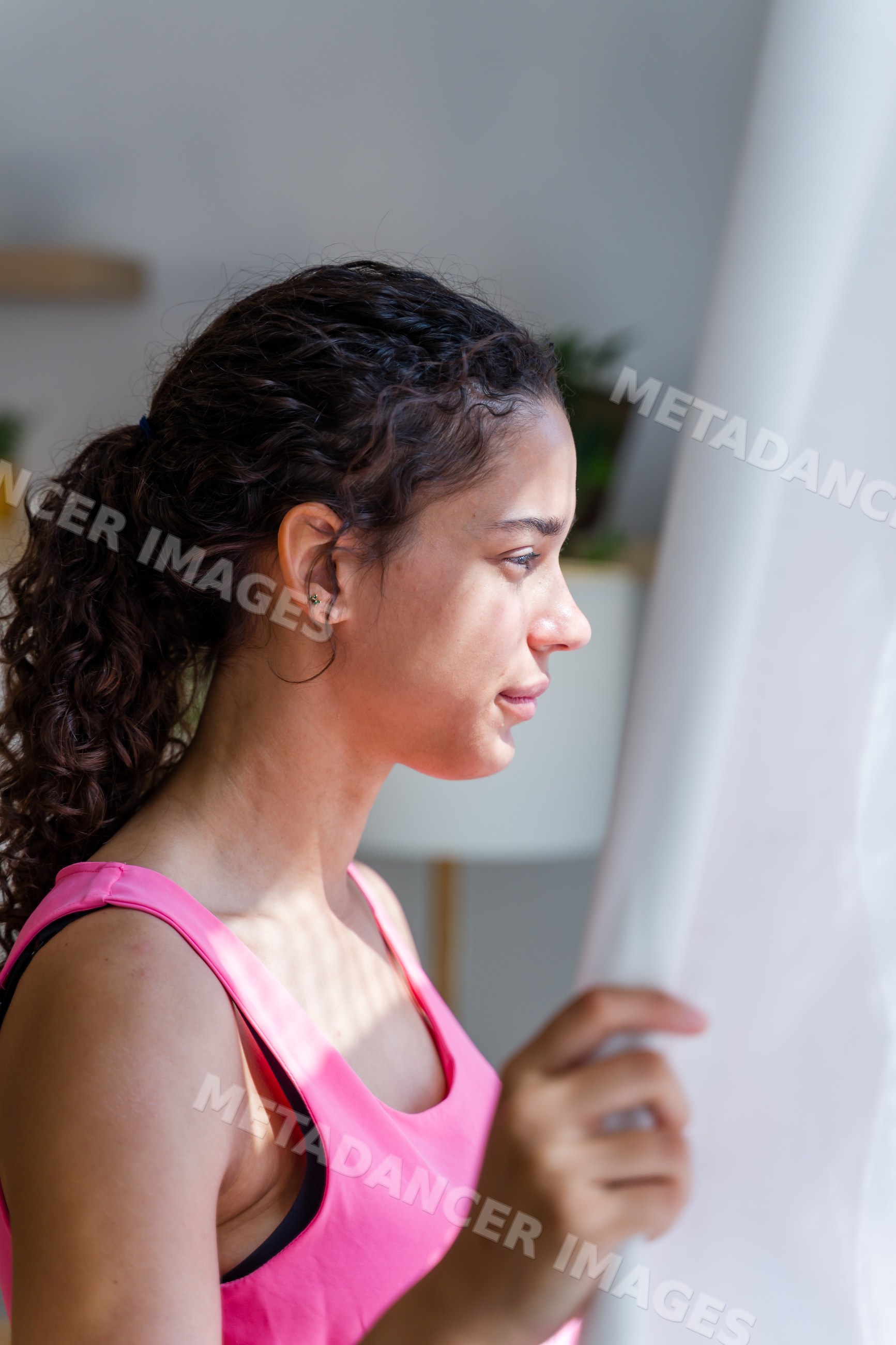 A young Hispanic woman looks out a window