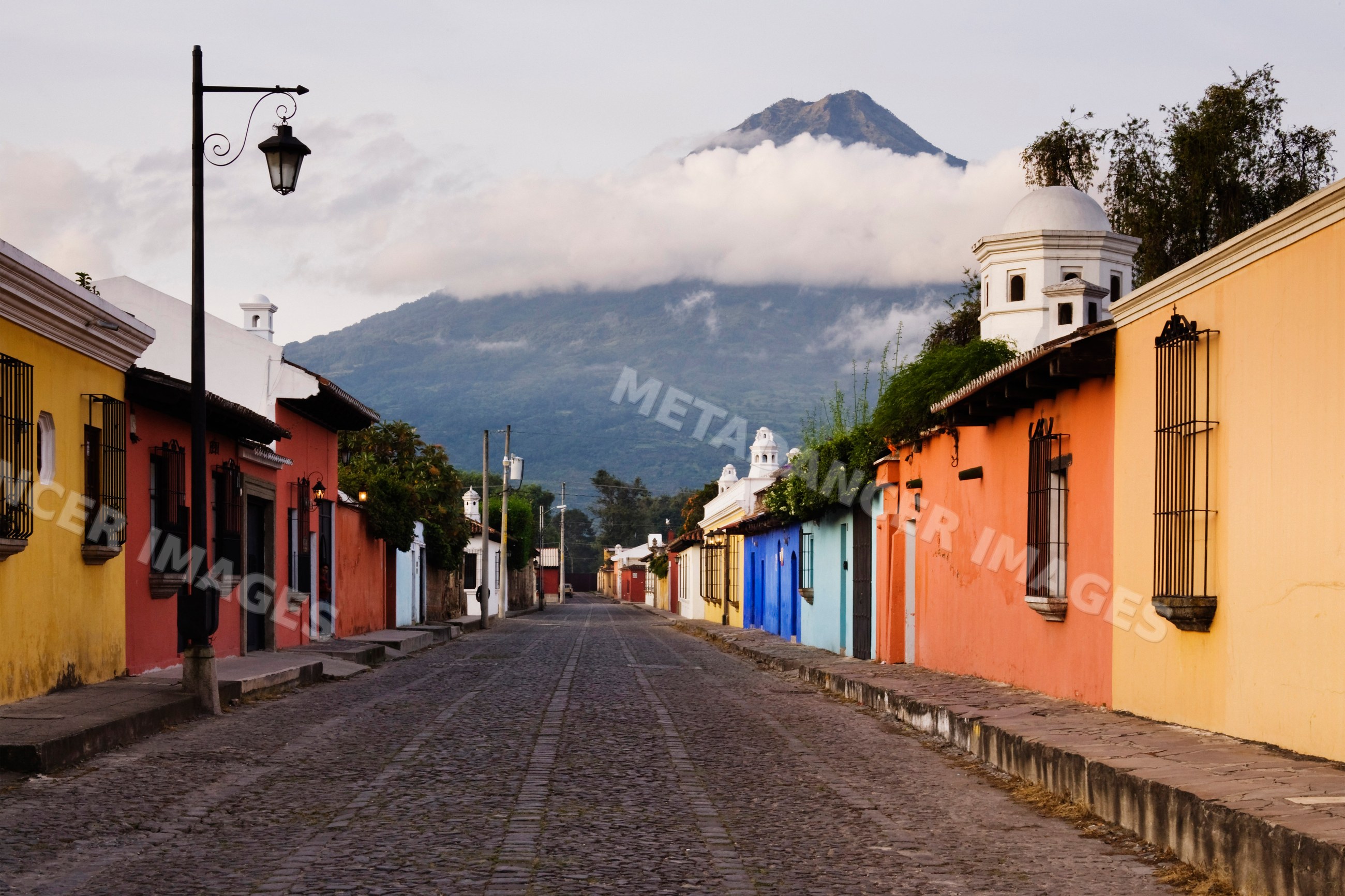 Volcano over cobblestone street and colorful houses guatemala