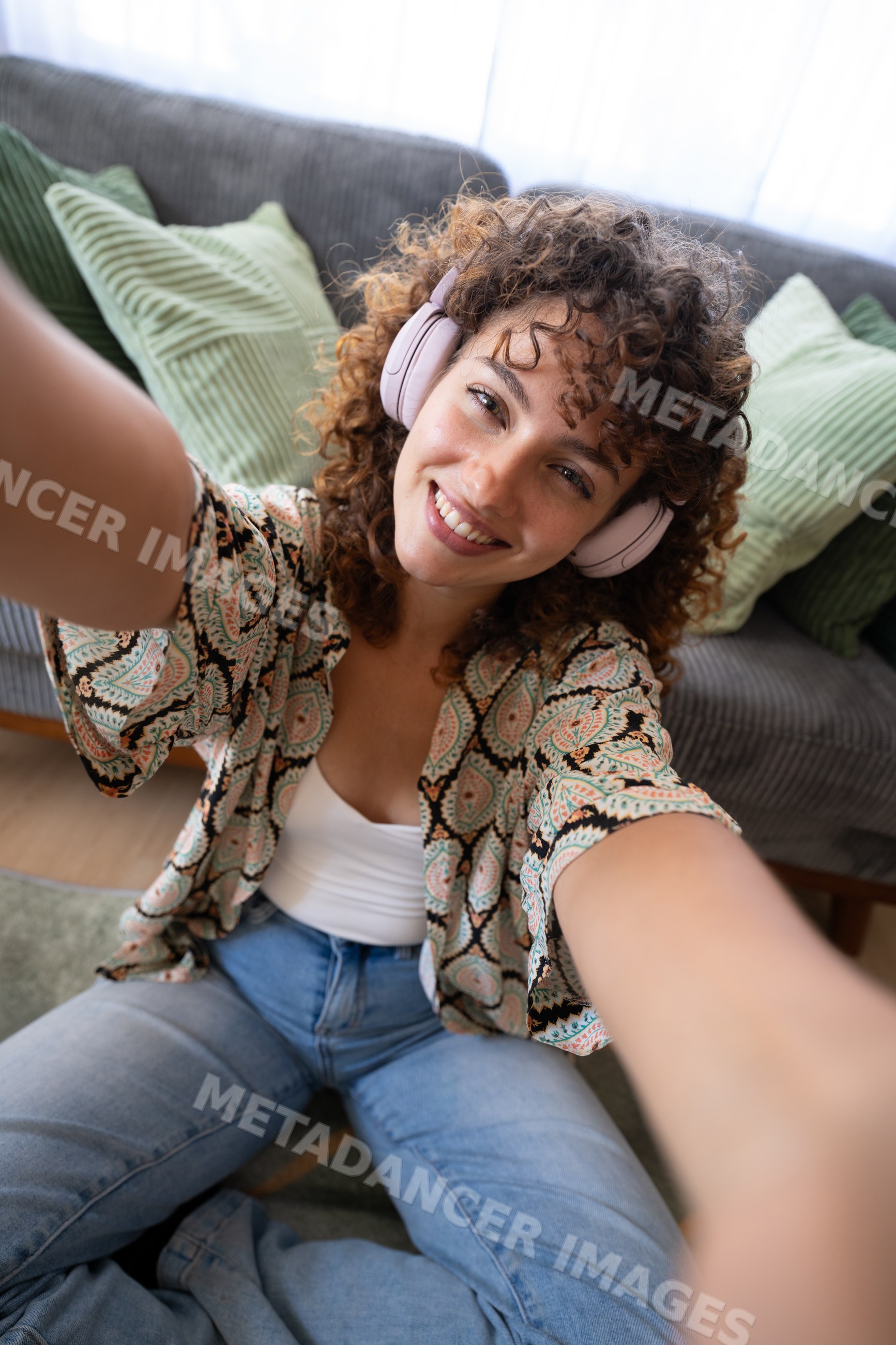 White woman taking selfie wearing headphones on couch