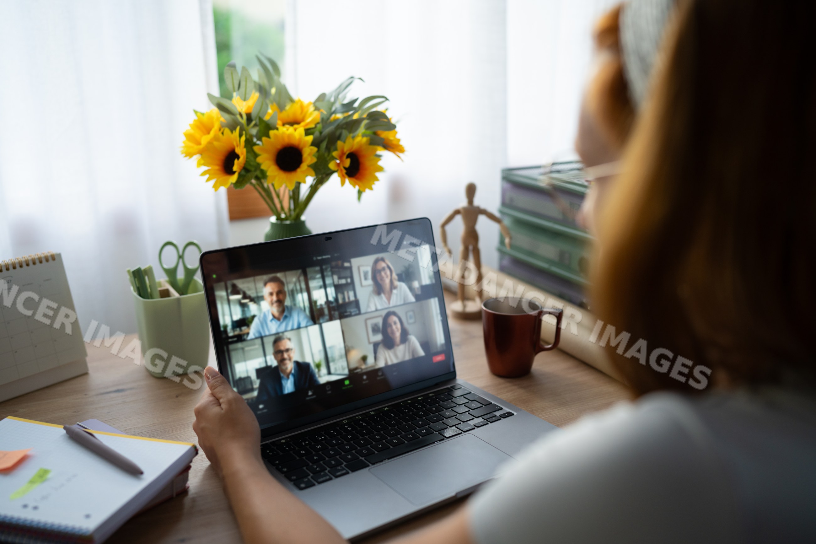 A white woman telecommutes with colleagues on a video call