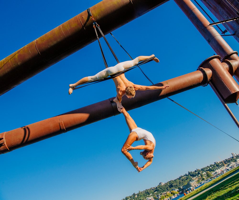 Aerial acrobats performing yoga on steel structure outdoors in a park