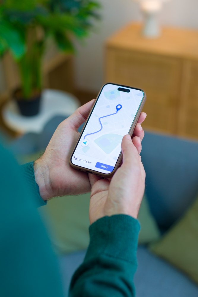 White person holding smartphone showing navigation route map indoors