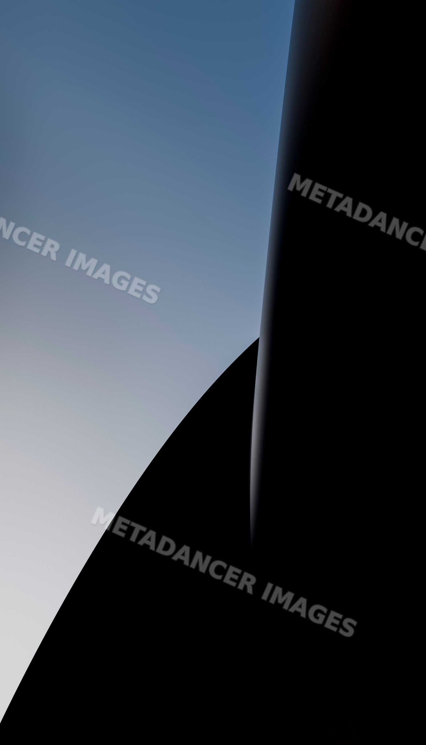 Sunlit aerodynamic airplane wingtip against clear blue gradient sky