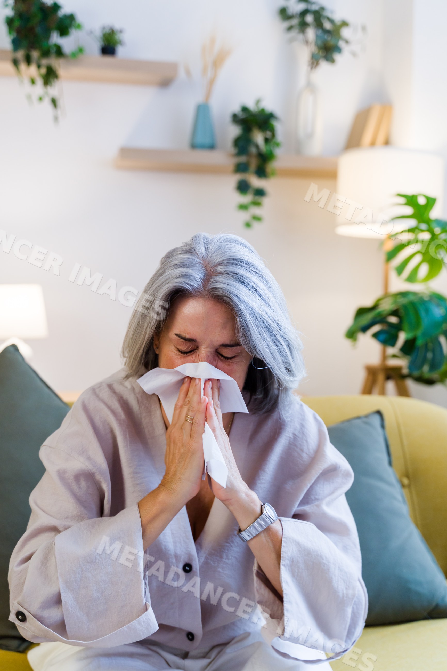 Older white woman sneezing on sofa in living room