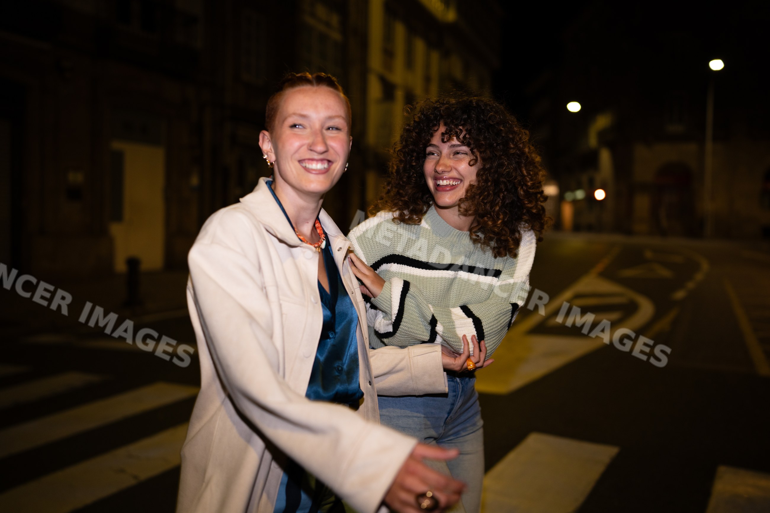 Two white women laughing during night walk on a Santiago De Compostela