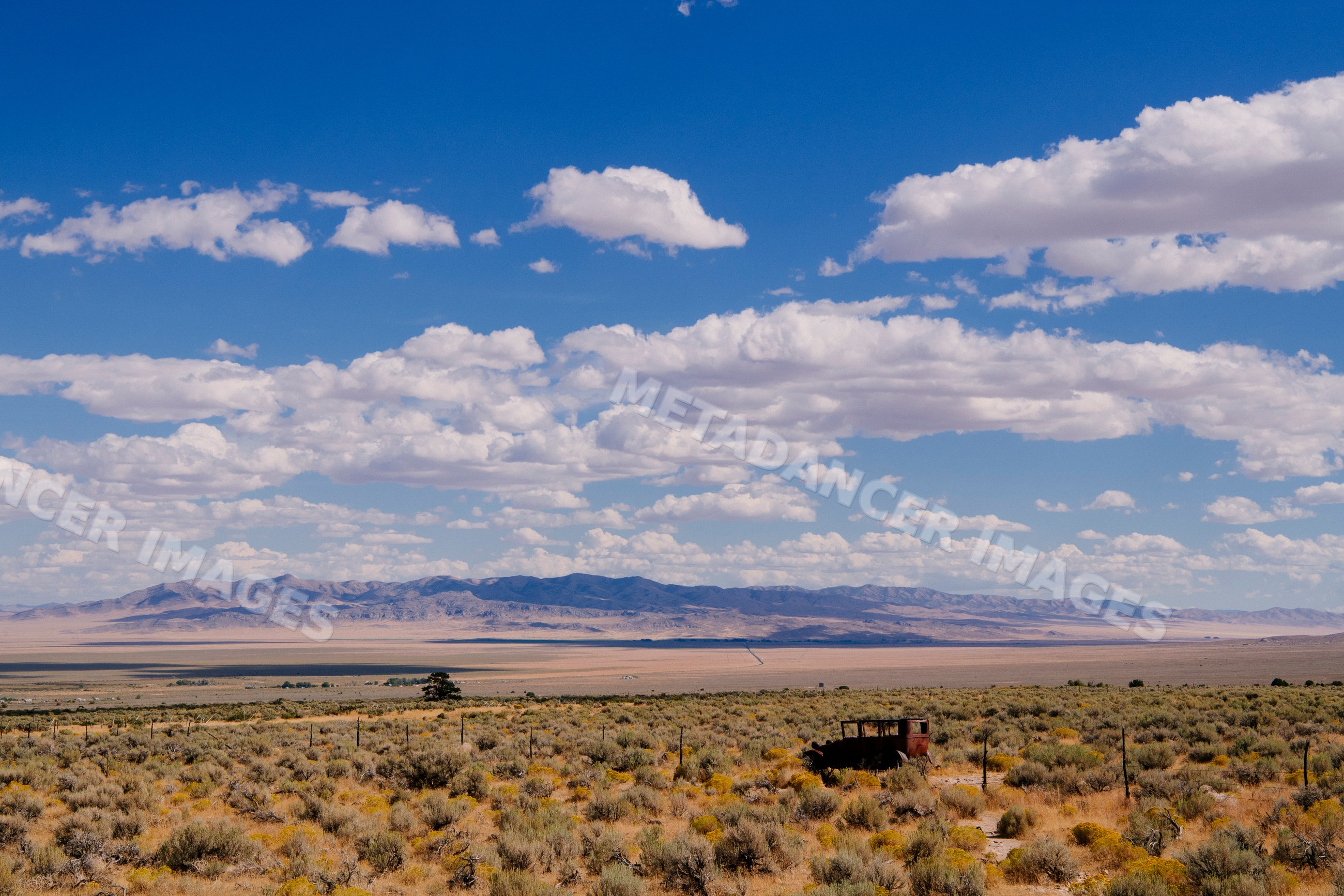 Nevada desert landscape with rusted vehicle and mountains