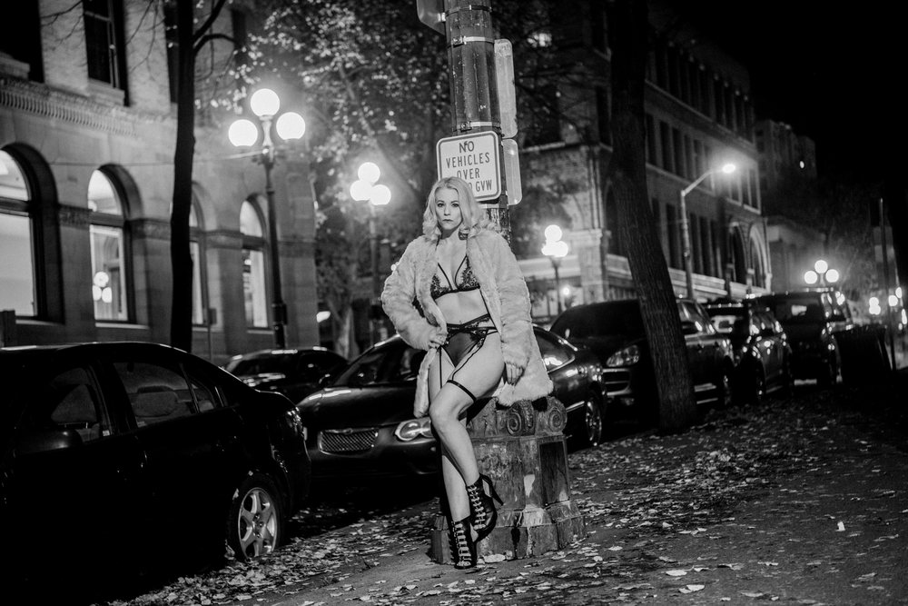 White woman posing in lingerie and fur coat on Seattle city street
