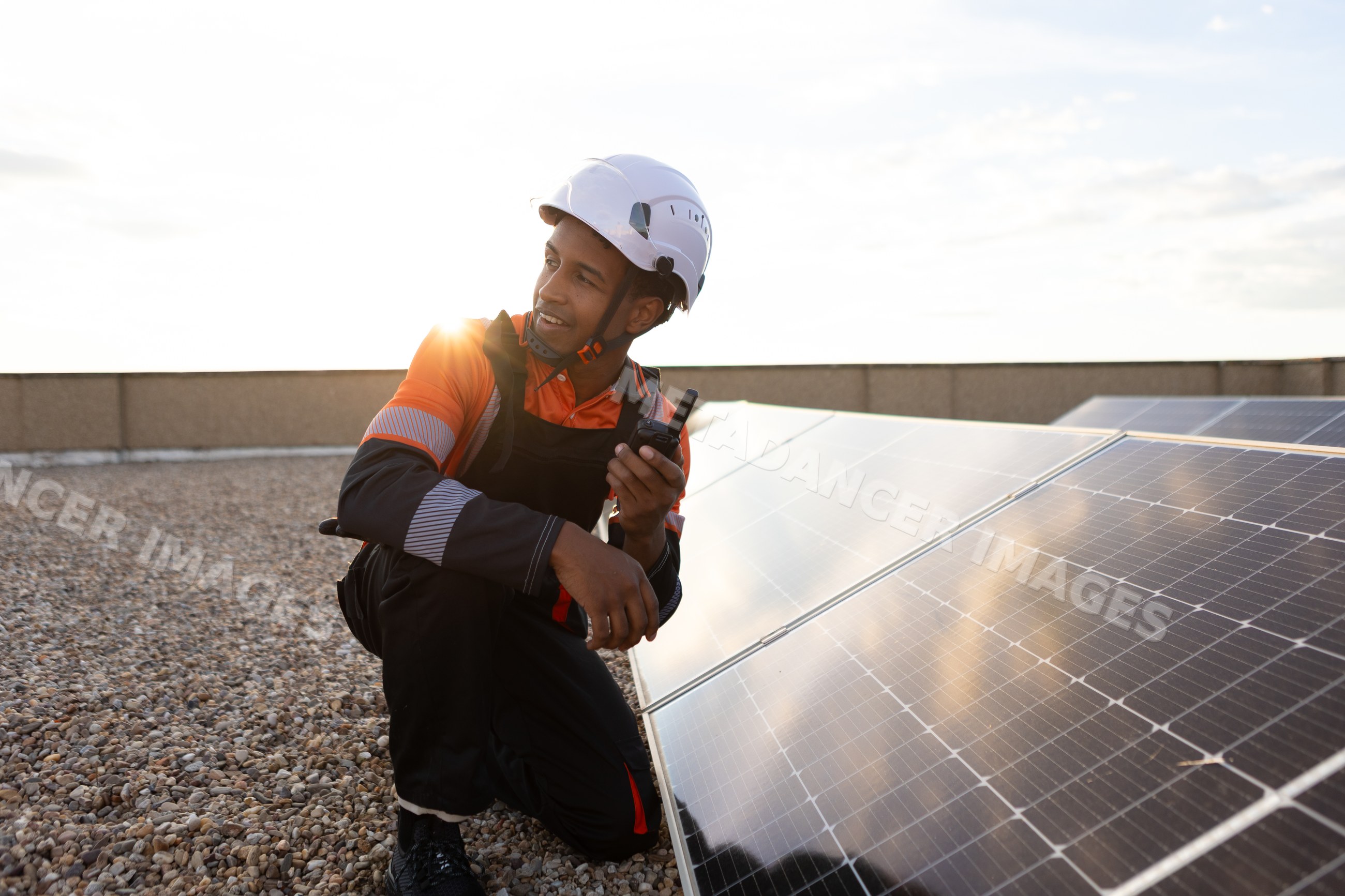 Worker inspecting solar panels on roof at sunset in Madrid, Spain