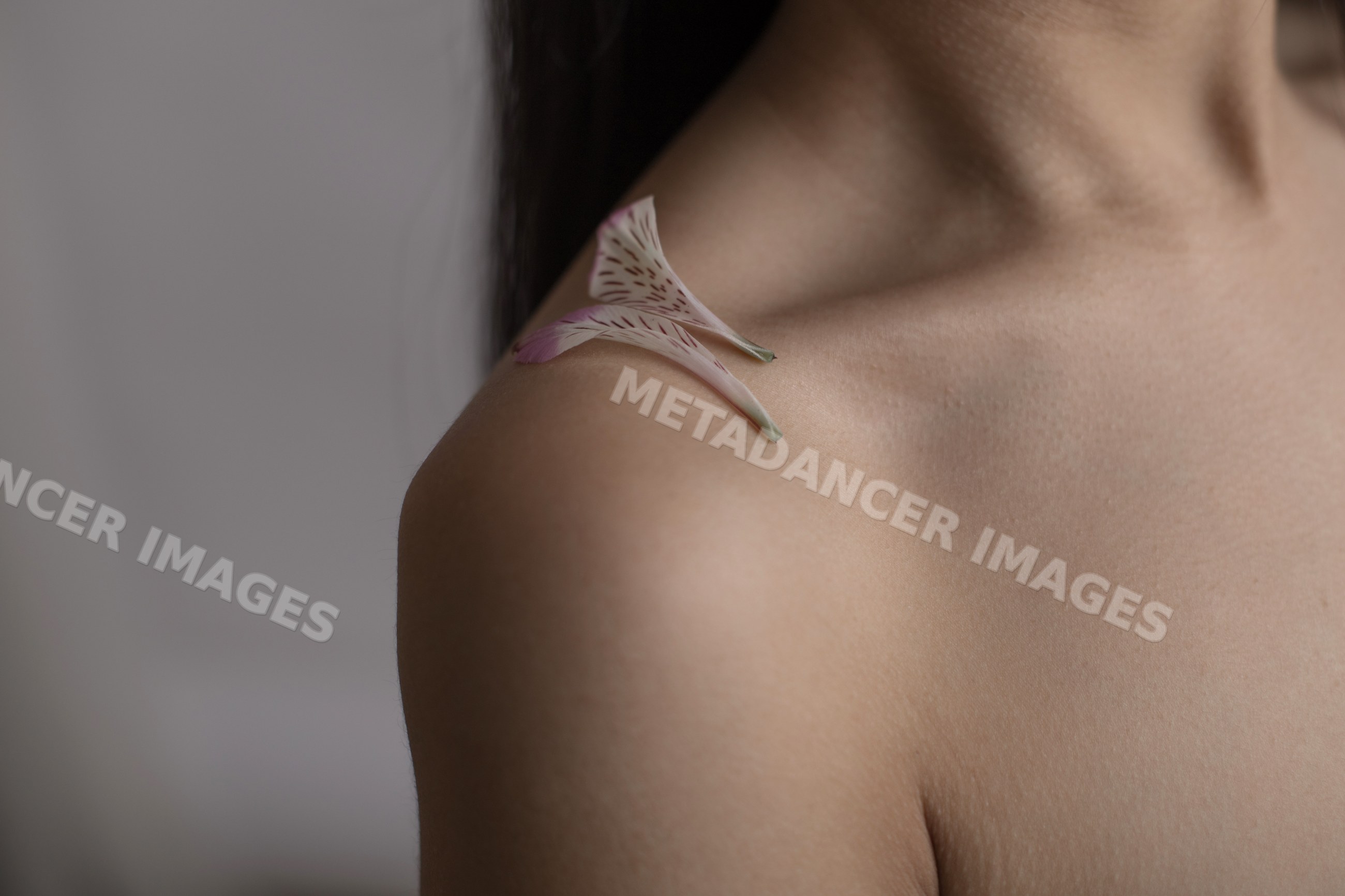 Close-up of shoulder with flower petals on smooth skin
