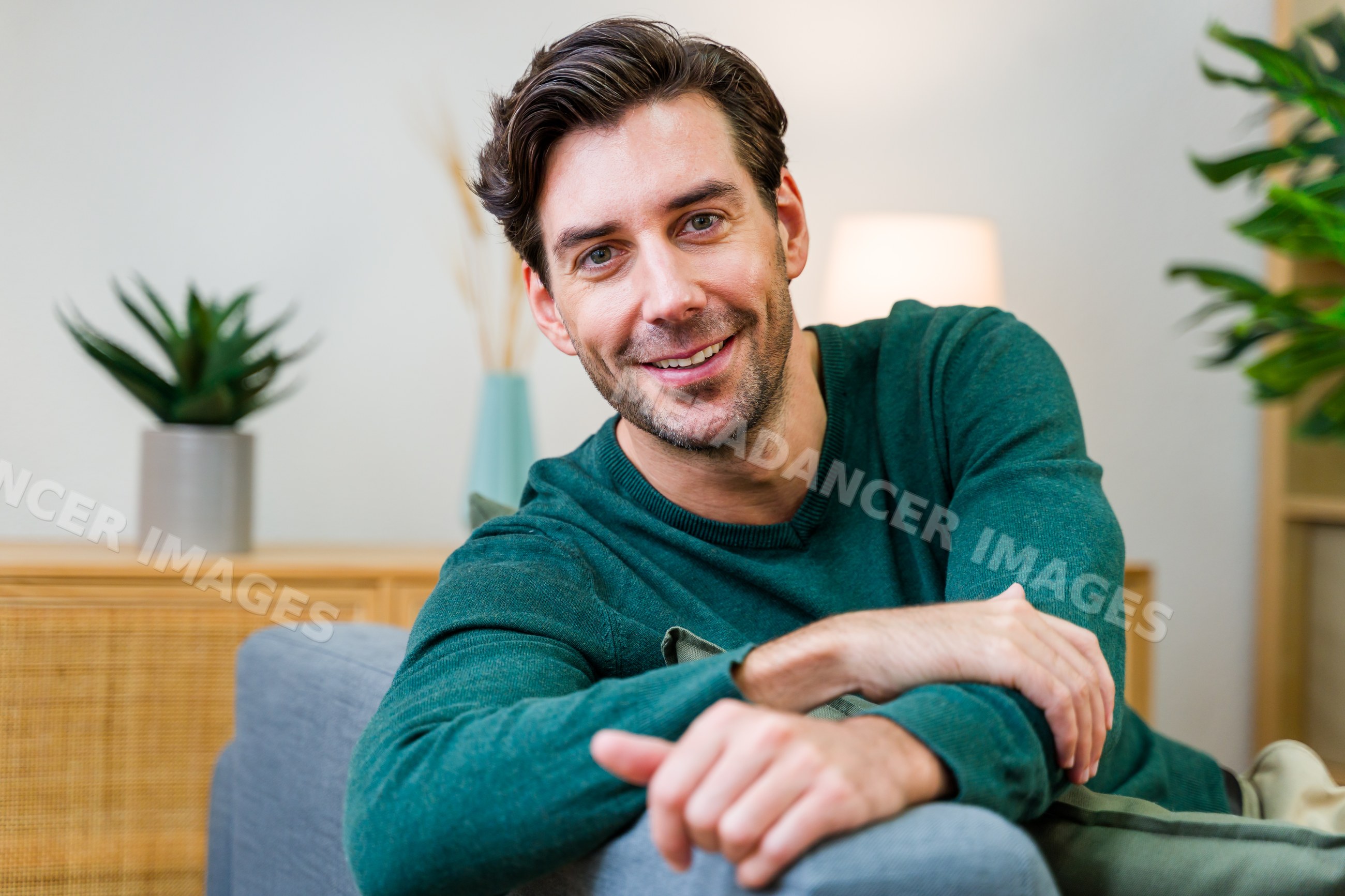 White man smiling and relaxing on couch in living room interior