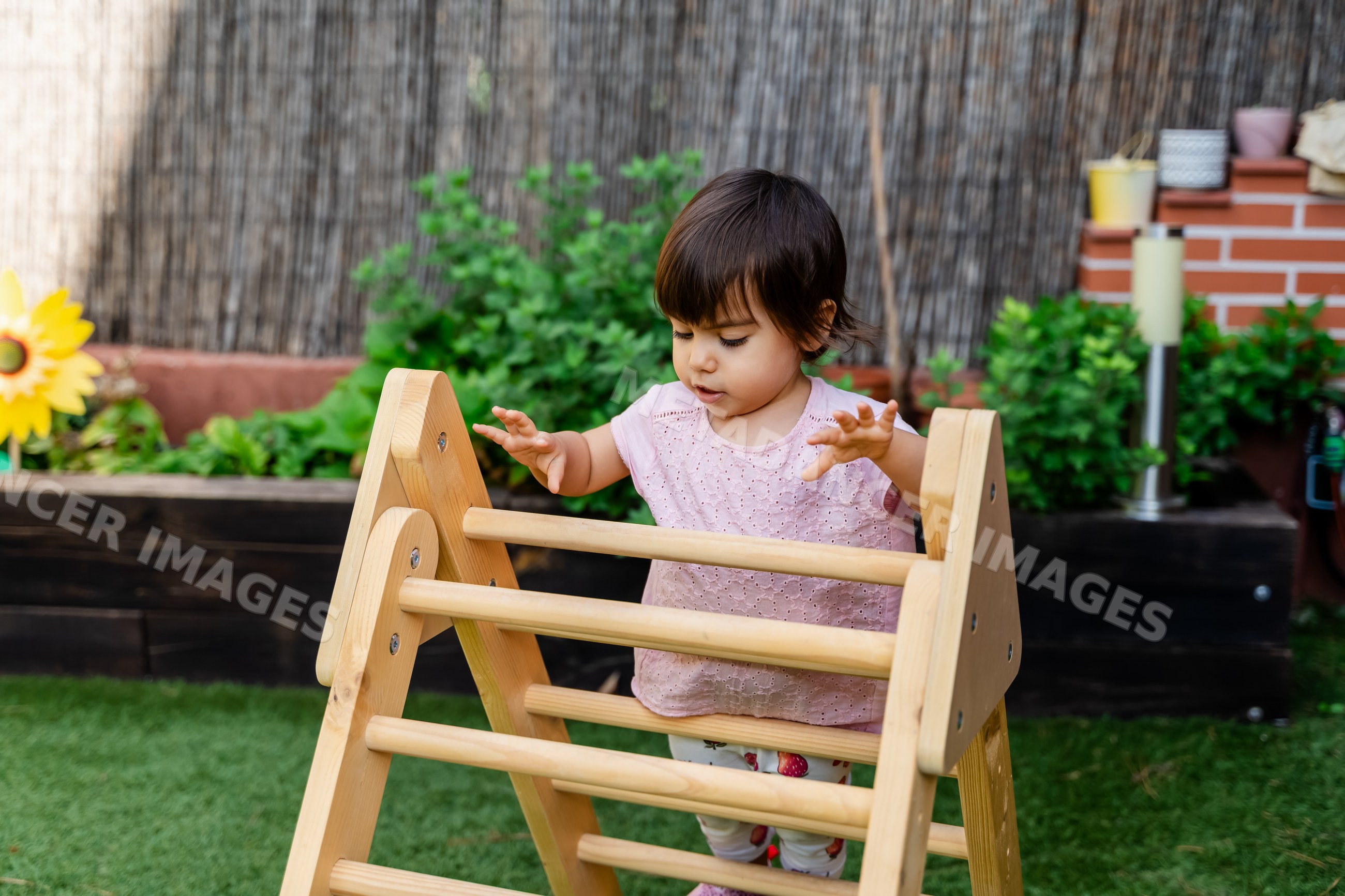 Toddler white girl playing on wooden climber playground toy