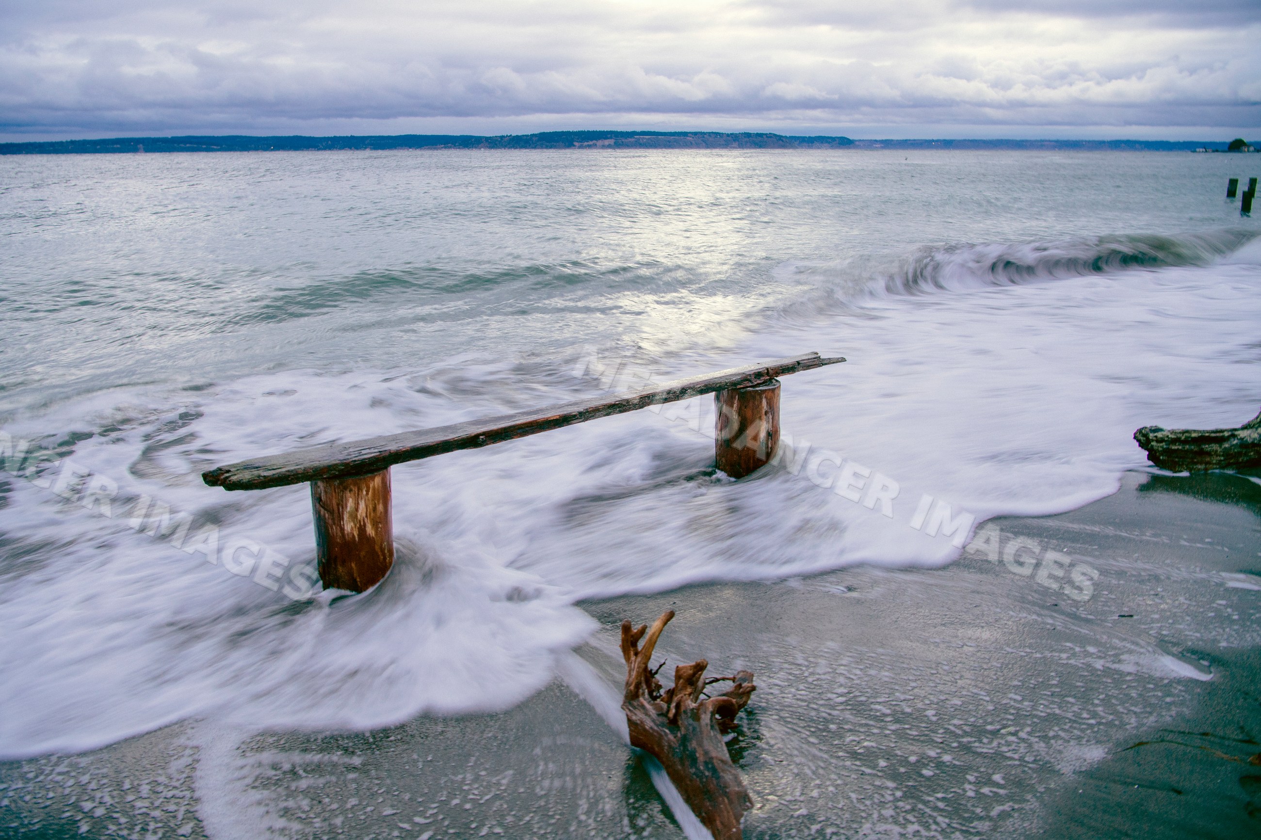 Wood bench on shoreline with waves at Norwegian Point washington