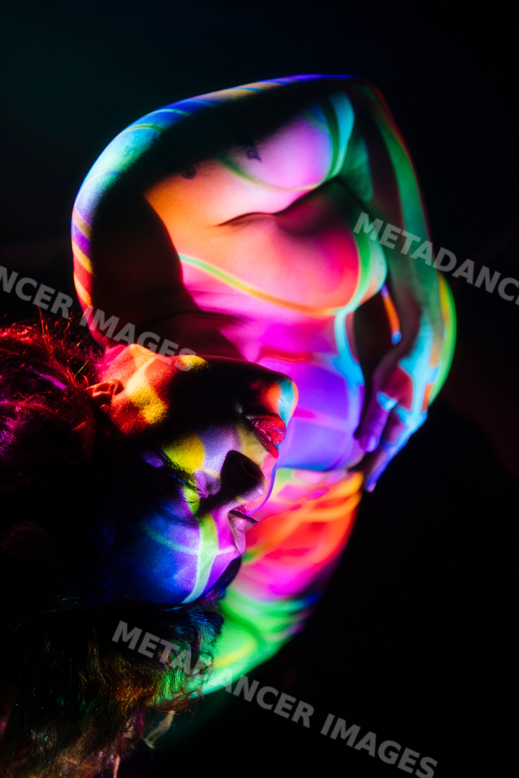 Pregnant white woman with colorful projected light pose