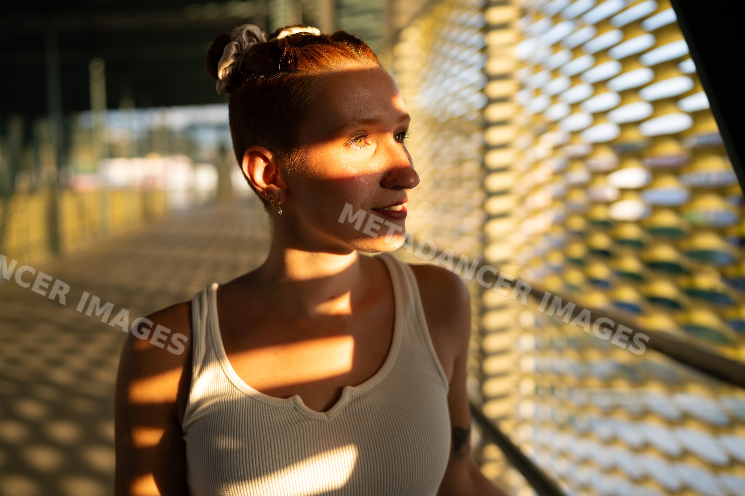 Young white woman stands in sunlight casting patterned shadows