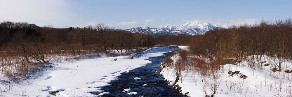 Stream flowing through snow-covered landscape on shiretoko peninsula