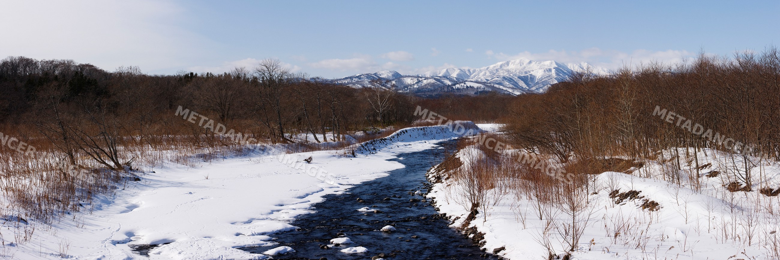 Stream flowing through snow-covered landscape on shiretoko peninsula
