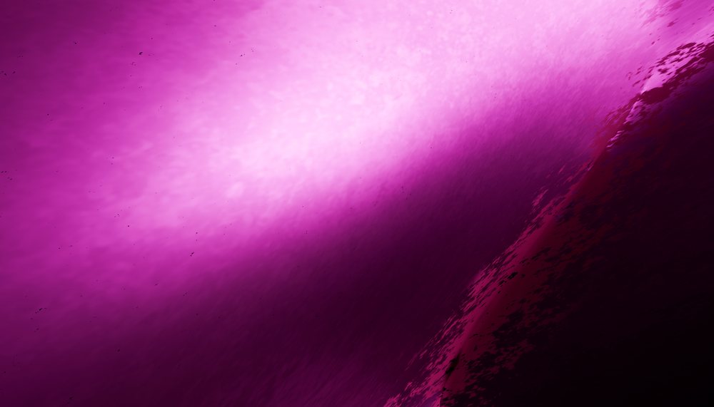 Close-up of a purple ocean wave curling with textured water surface