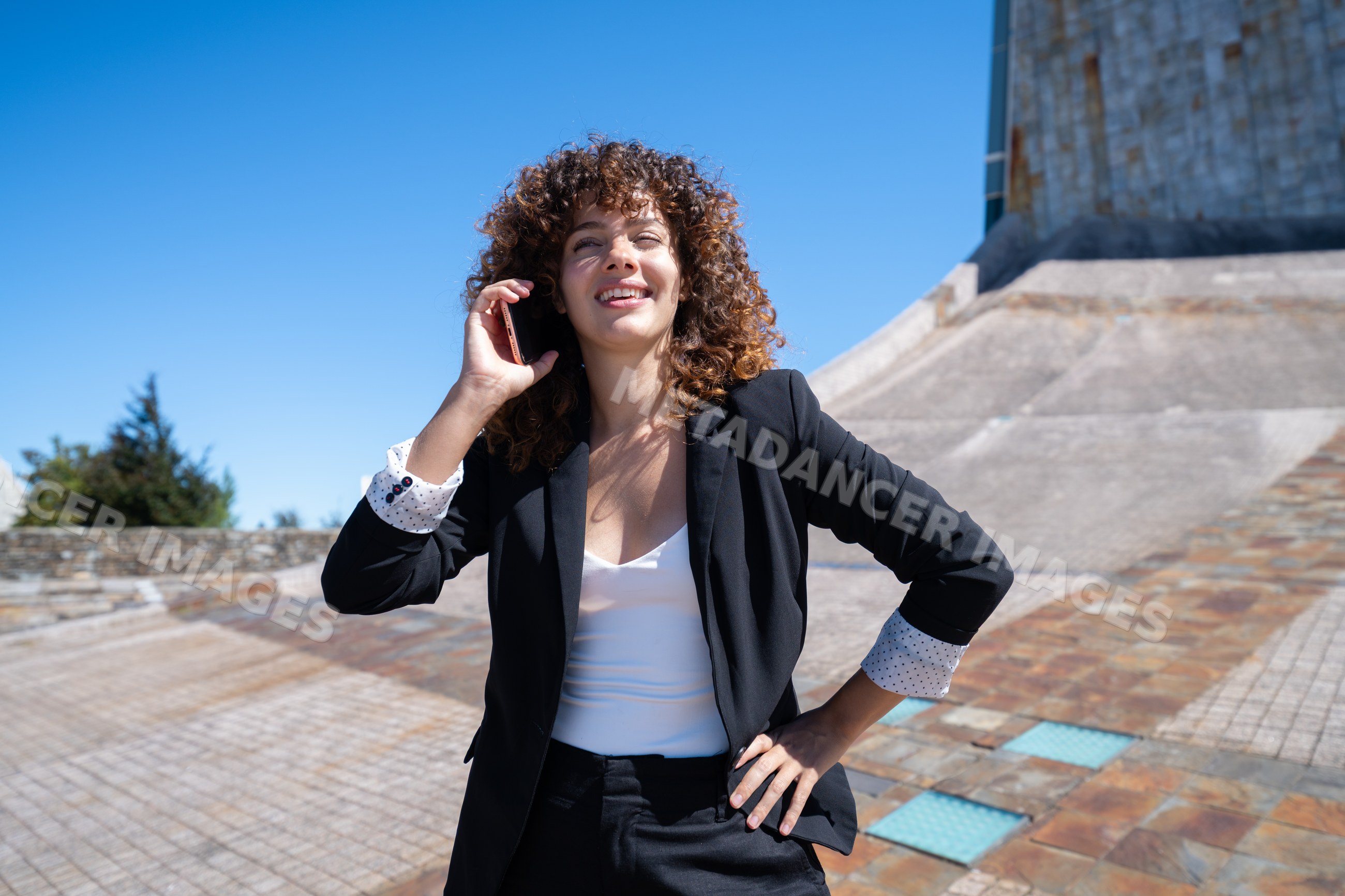 Businesswoman talking on phone outdoors by modern stone architecture