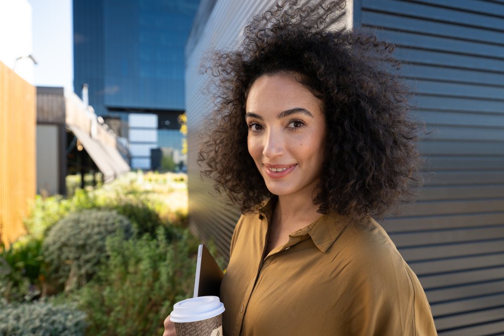 Woman holding coffee cup and tablet outdoors in urban environment
