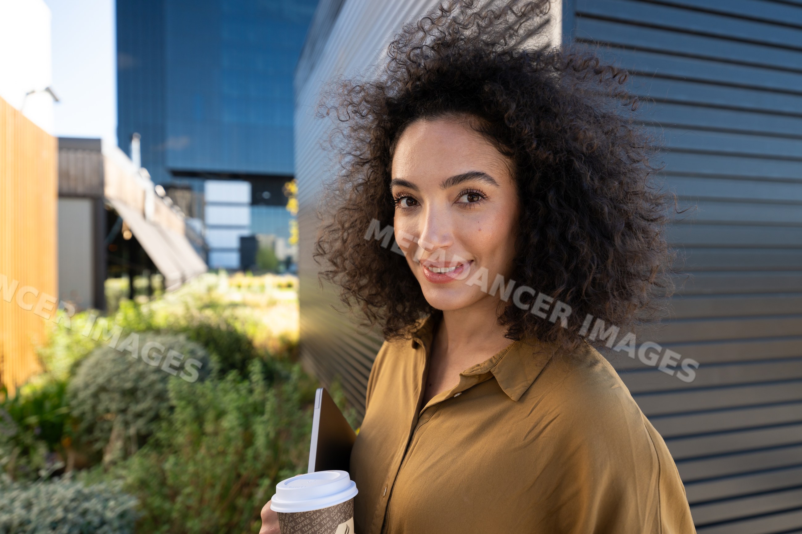 Woman holding coffee cup and tablet outdoors in urban environment