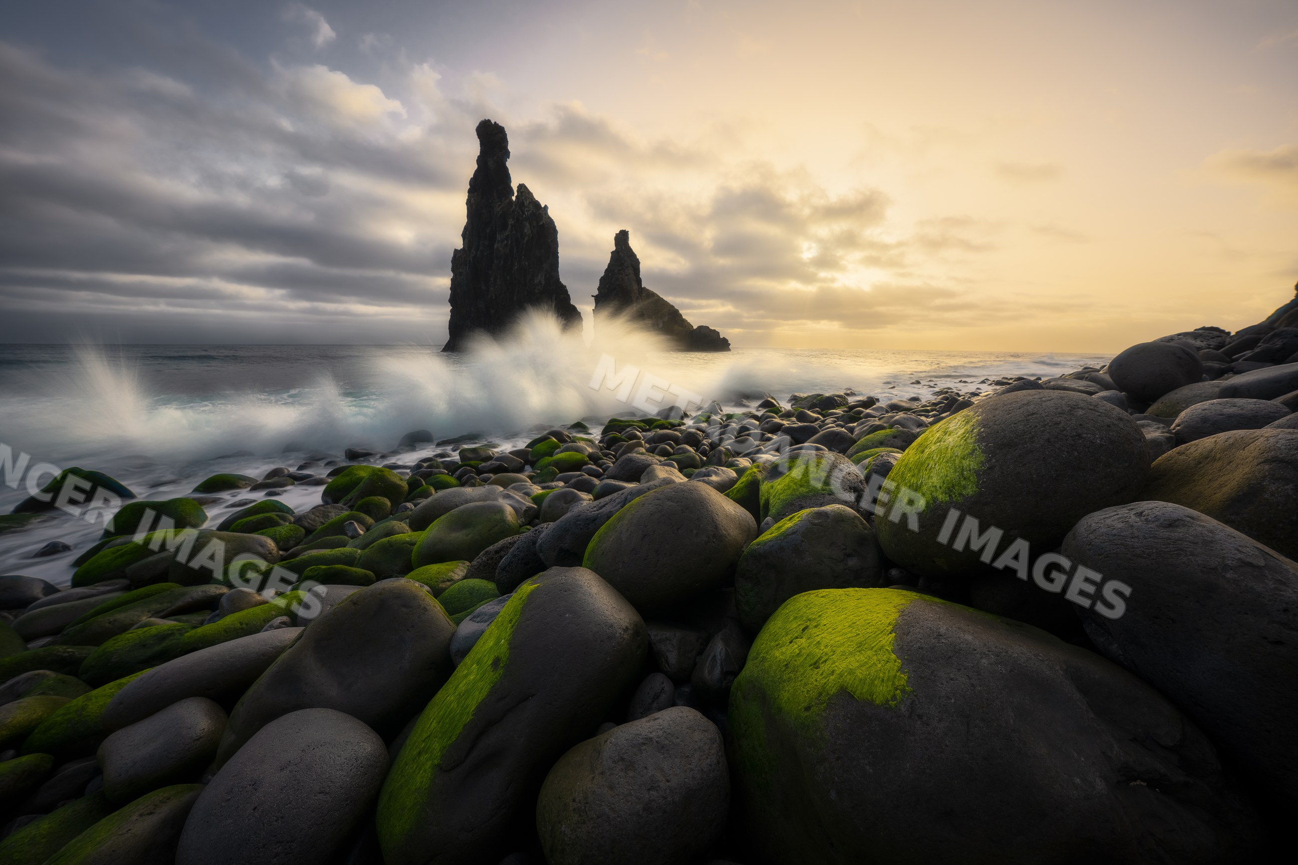 Waves crash on mossy rocky shore and sea stacks