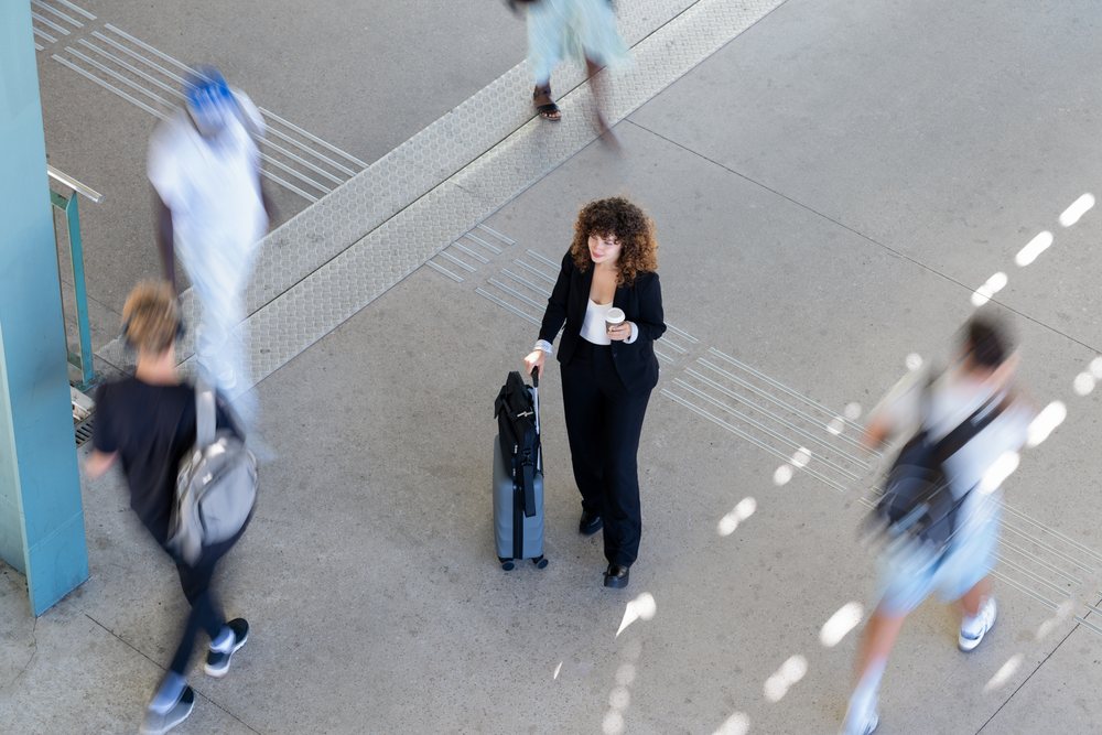 White woman walking with suitcase and coffee cup