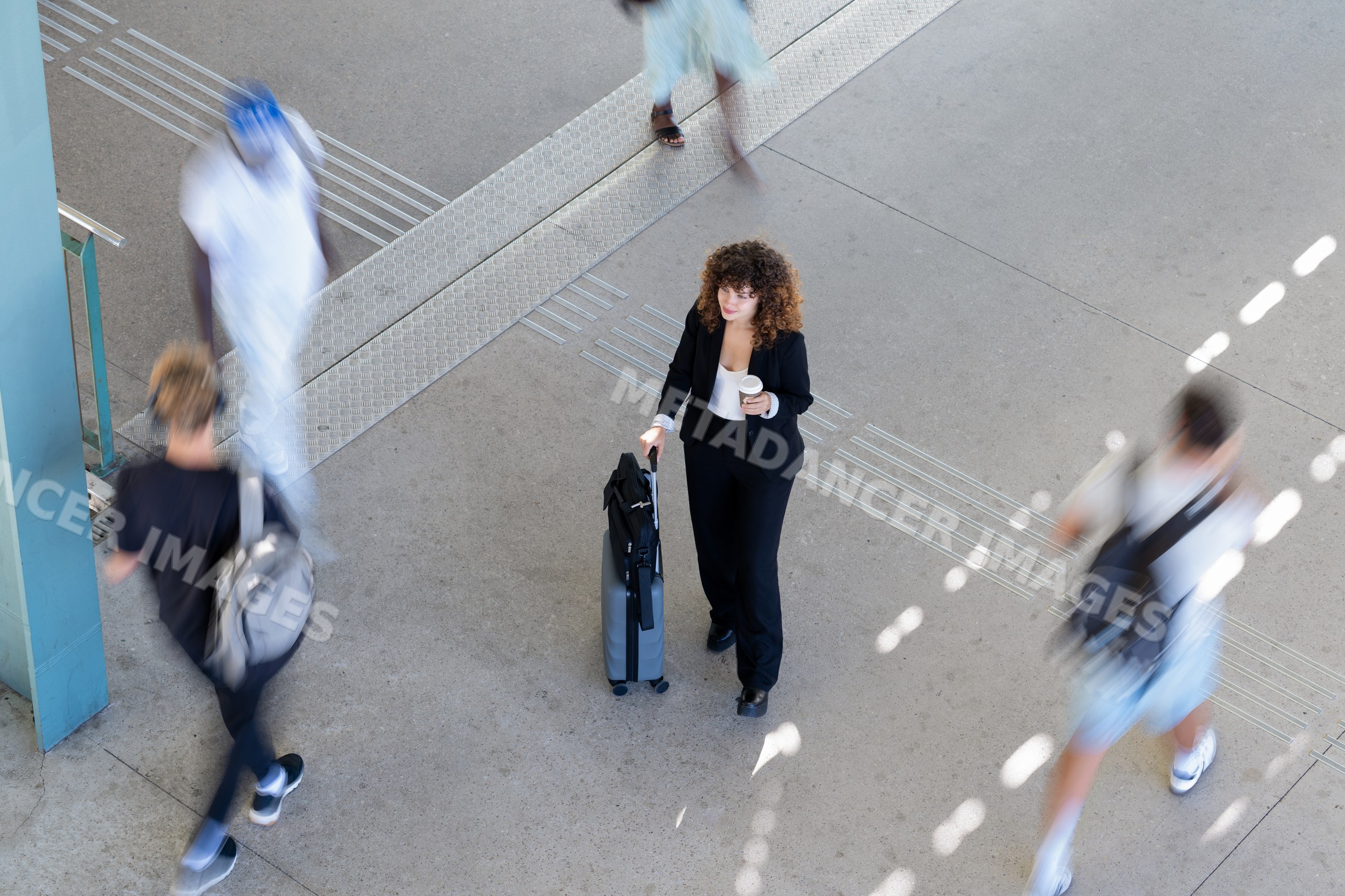 White woman walking with suitcase and coffee cup