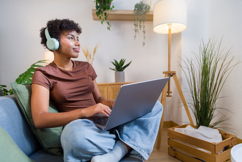Young African American woman using laptop with headphones
