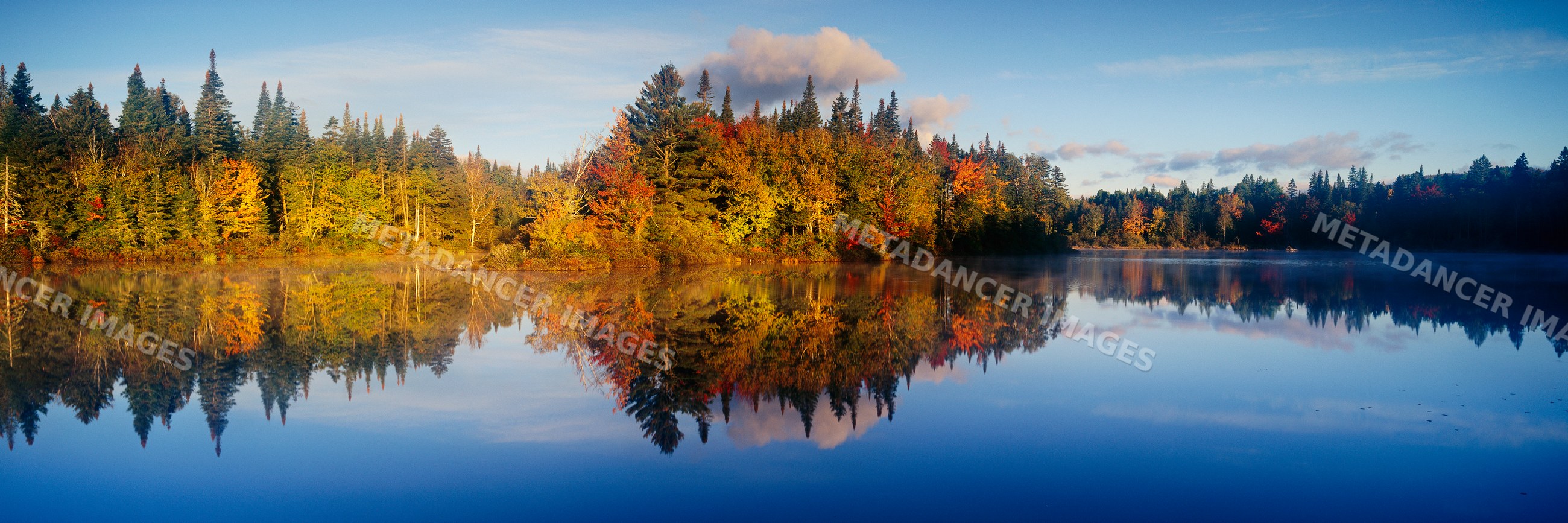 Fall landscape with colorful trees reflecting on calm lake
