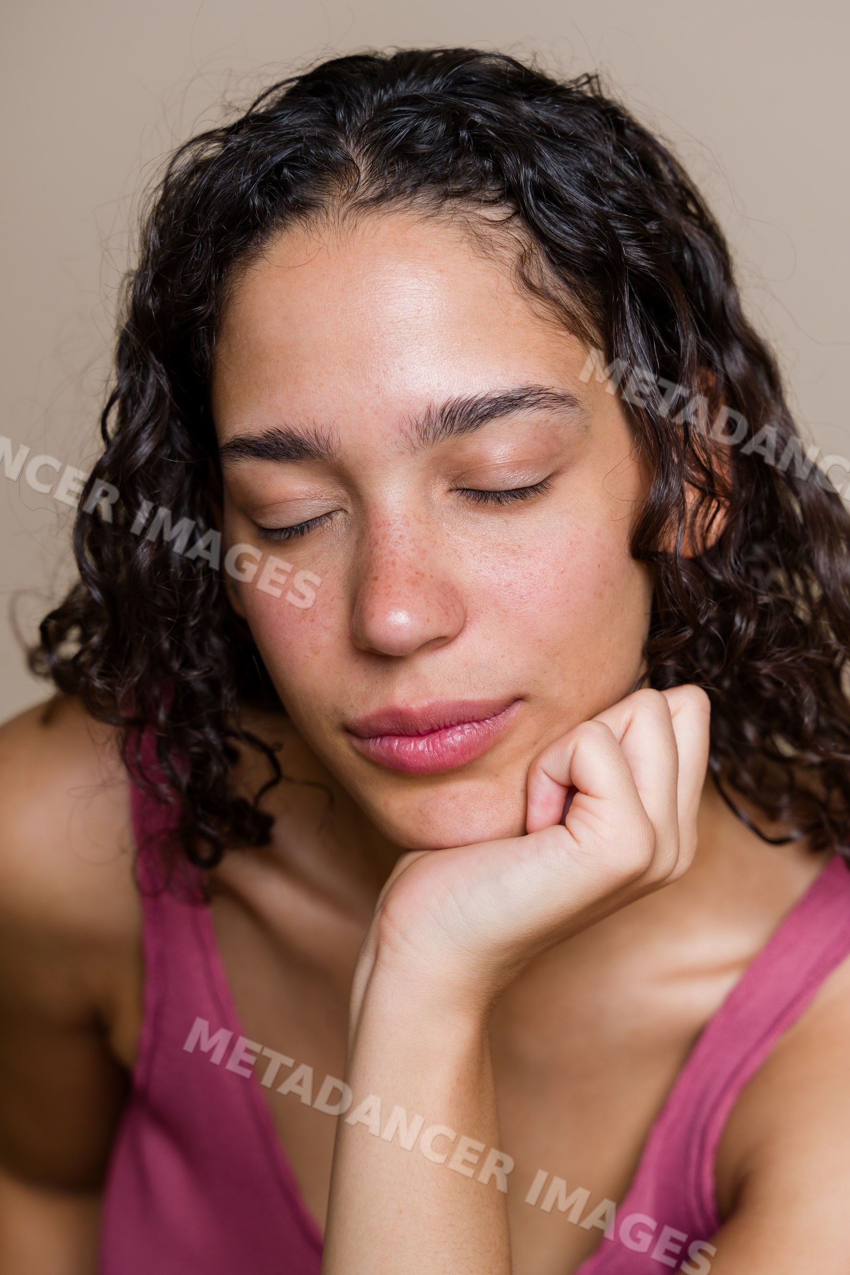 Portrait of a Hispanic woman with closed eyes resting hand on chin