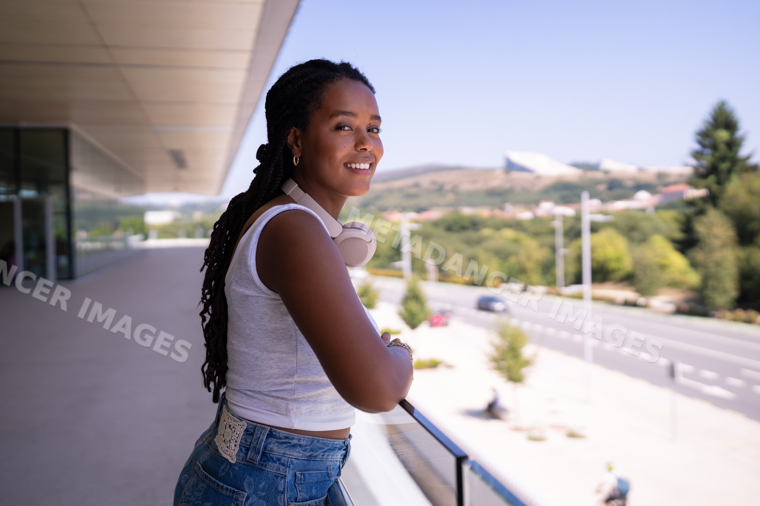 A young African American woman smiles outdoors on a balcony