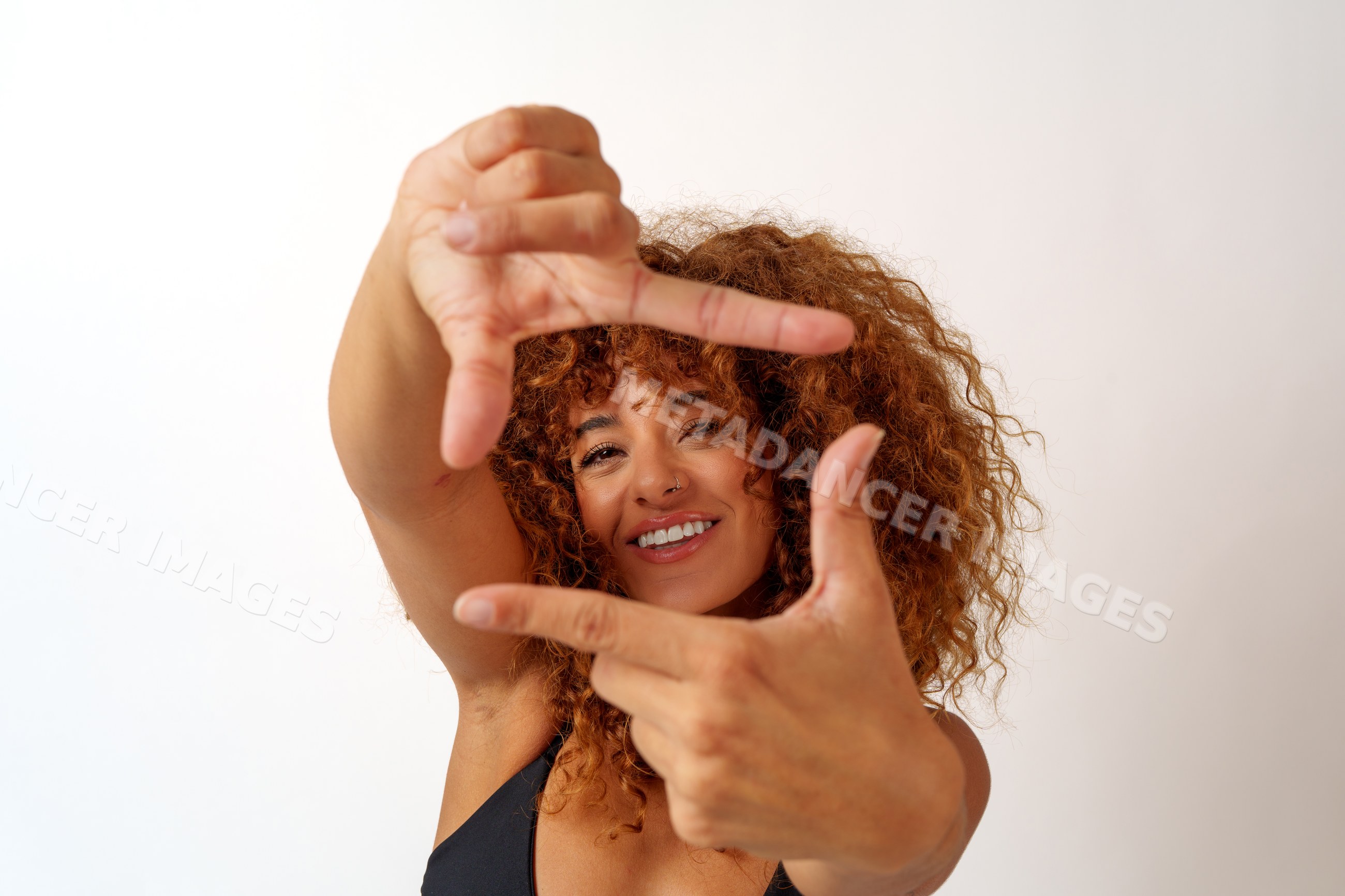 Hispanic woman framing face with hands and smiling