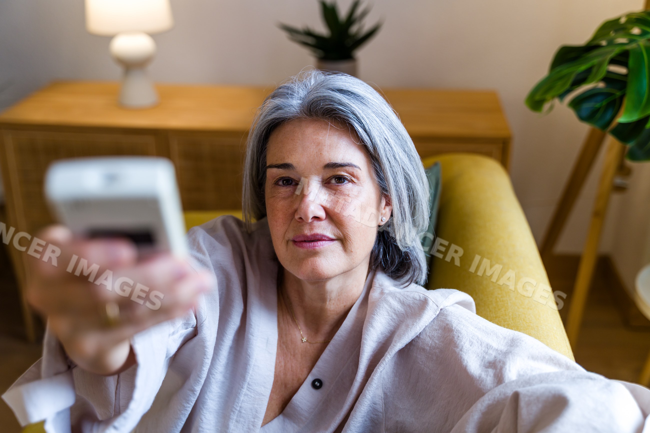 Middle-aged white woman holding remote control in modern living room
