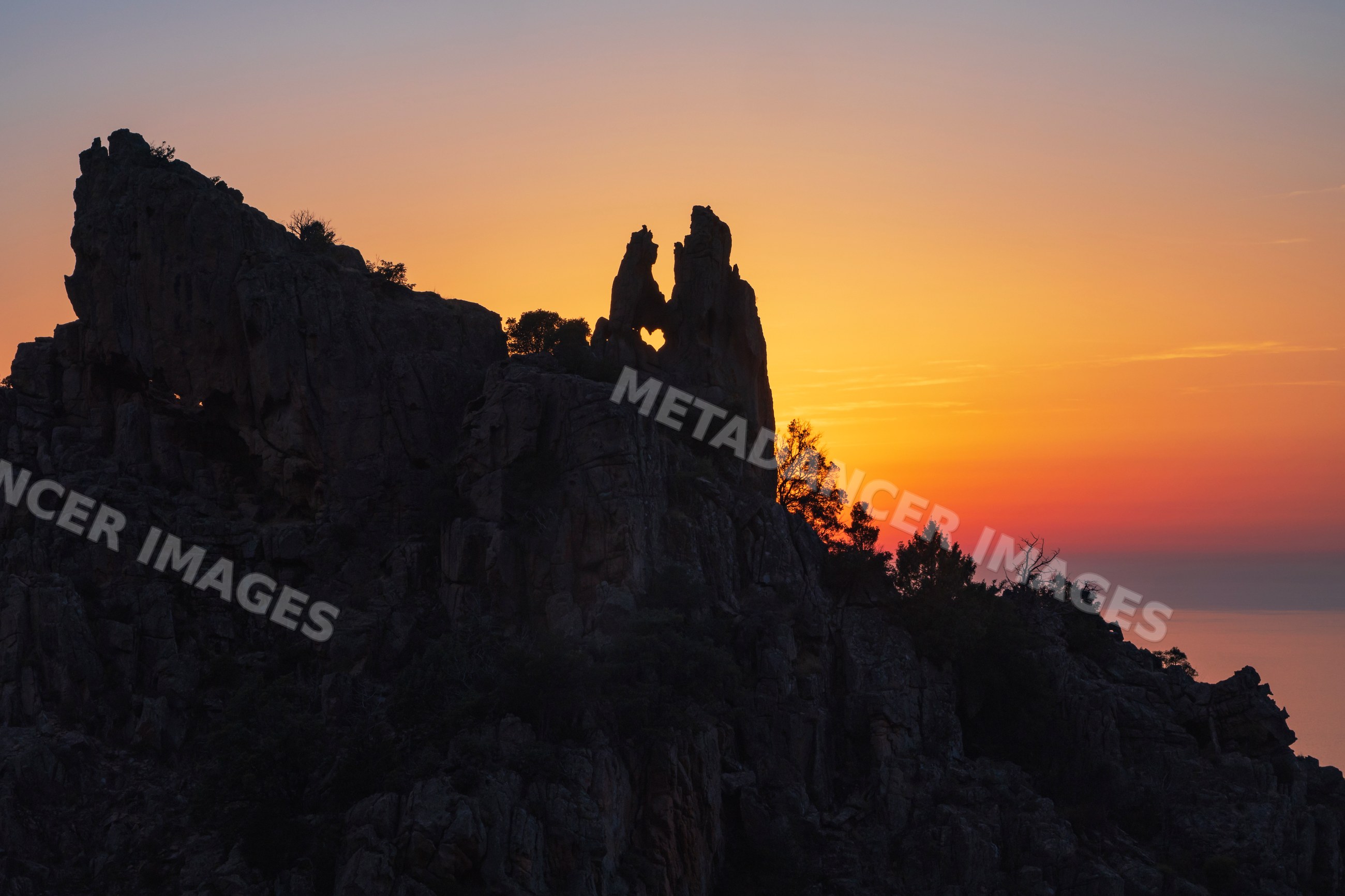 Rock formation with heart-shaped hole at sunset